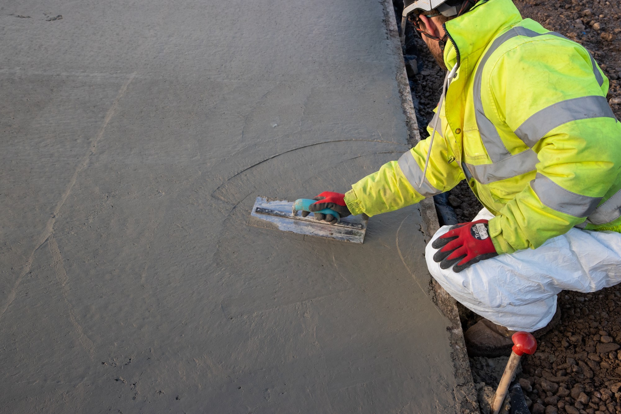 En av de viktigaste åtgärderna för att minska byggbranschens klimatavtryck är att utveckla betongen. Skanskas långsiktiga mål är att ta fram en klimatneutral betong. En byggnadsarbetare i högsynlighetskläder slätar ut färsk betong med en murslev.
