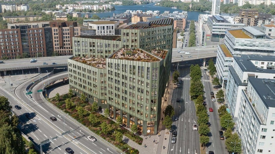 Flygfoto av moderna gröna kontorsbyggnader omgivna av vägar och grönska i stad.