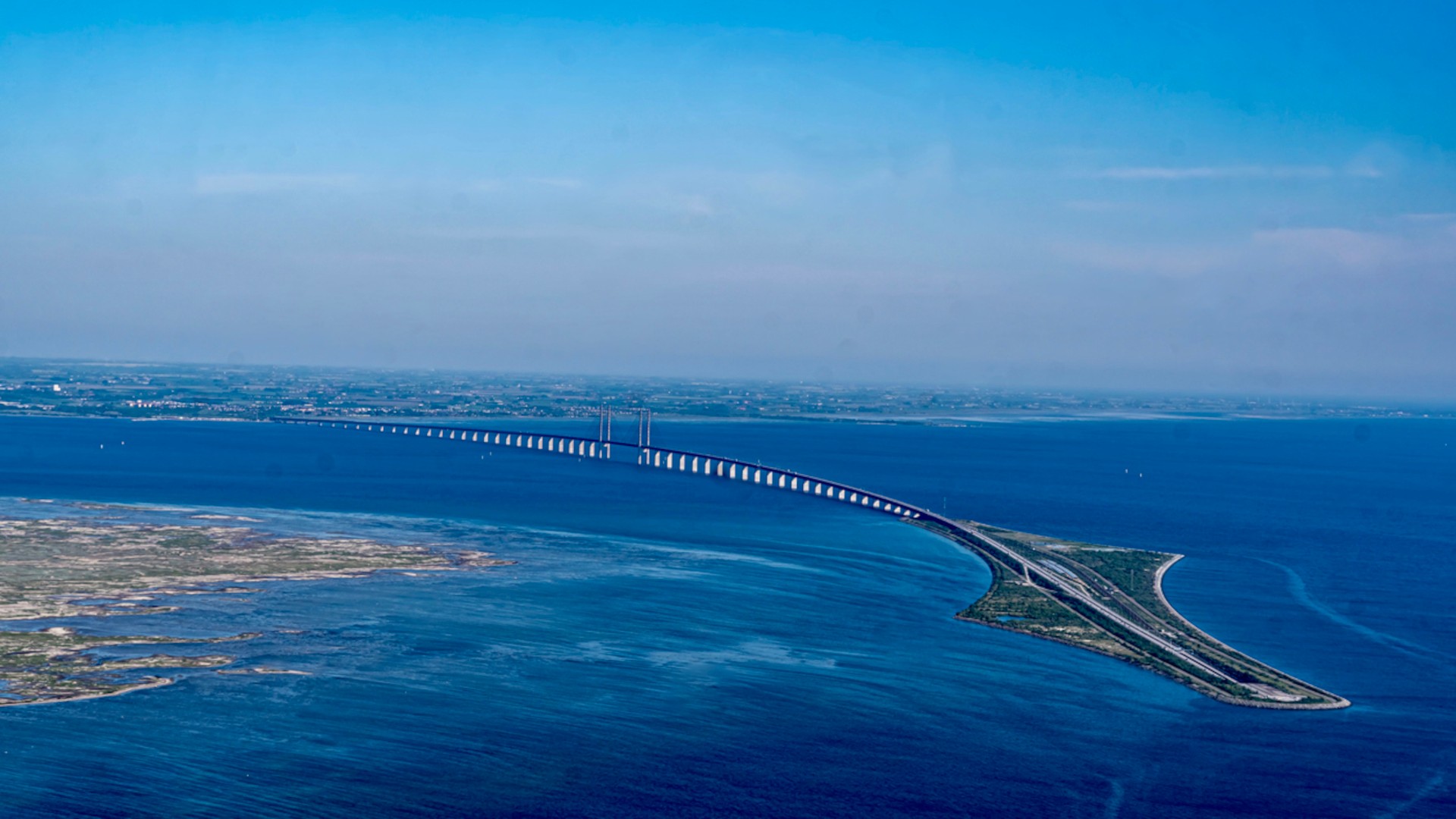 Flygfoto av Öresundsbron som förbinder Danmark och Sverige över det blå Öresund.