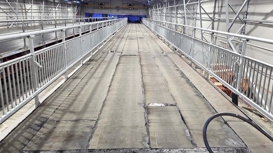 Industriellt tak med metallräcken och väderbitet betonggolv inuti lager.