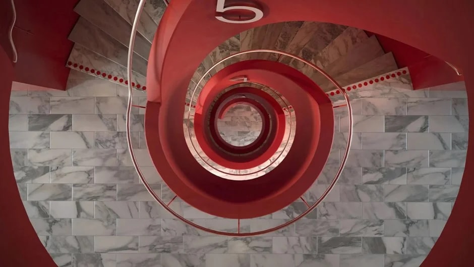 Toppvy av en röd spiraltrappa med marmorsteg och ett cirkulärt räcke.