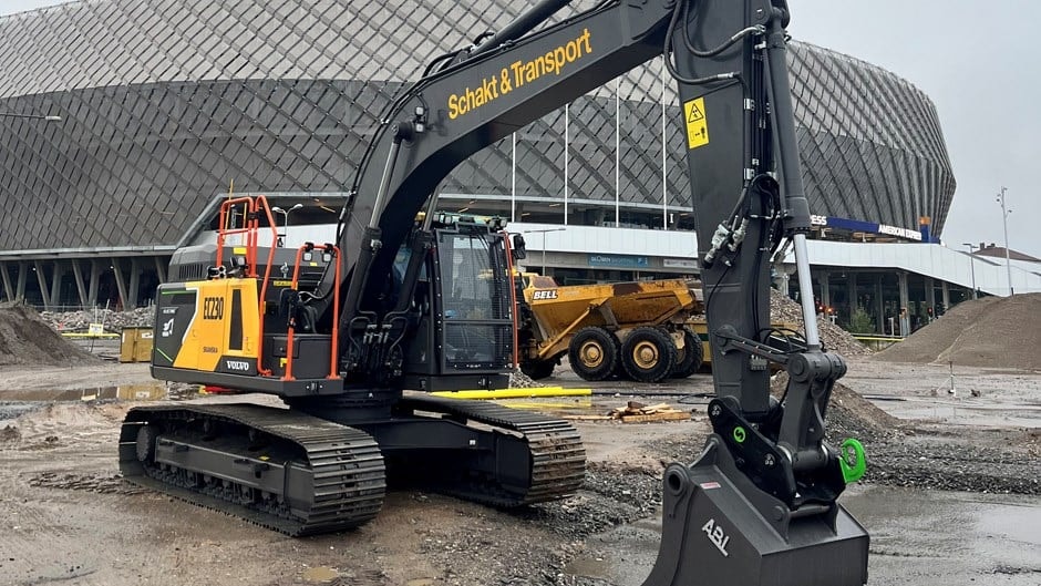 Svart Volvo-grävmaskin med Schakt & Transport-märkning på en byggarbetsplats.