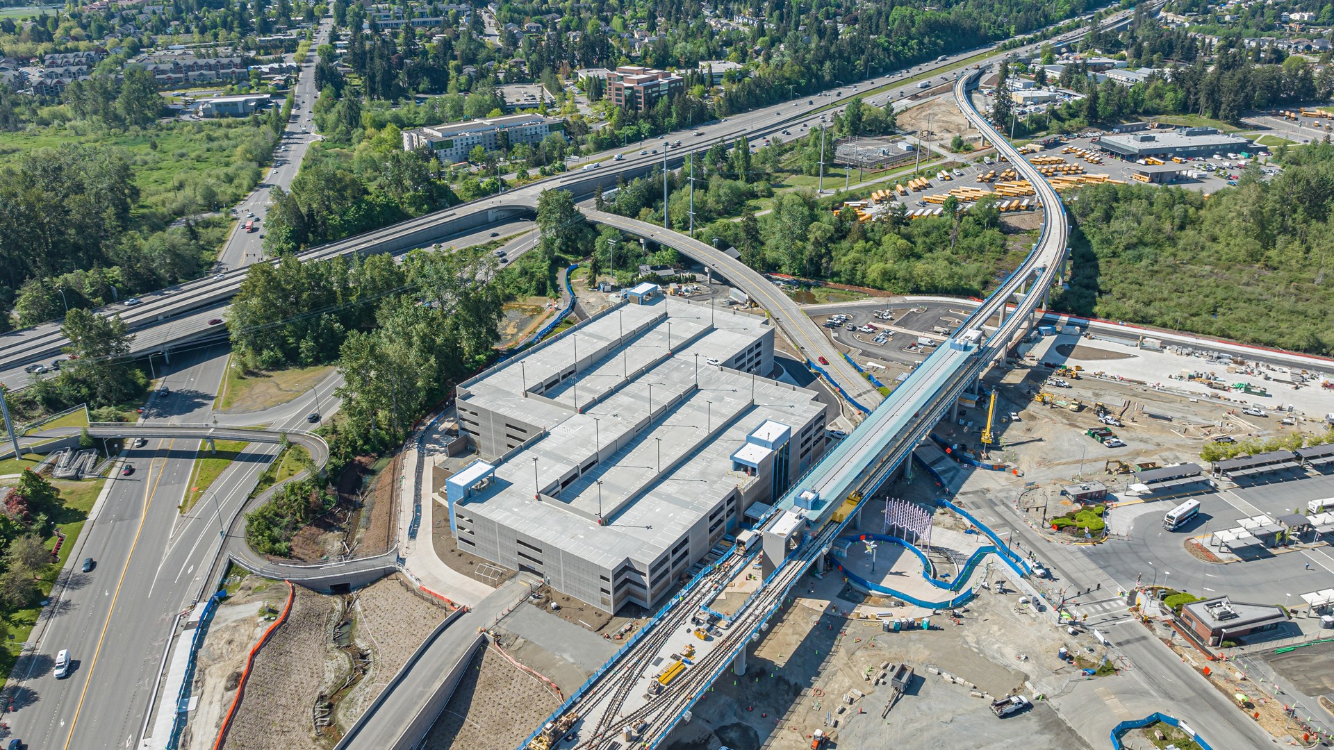 Aerial view of a construction site with a large building and nearby road infrastructure.