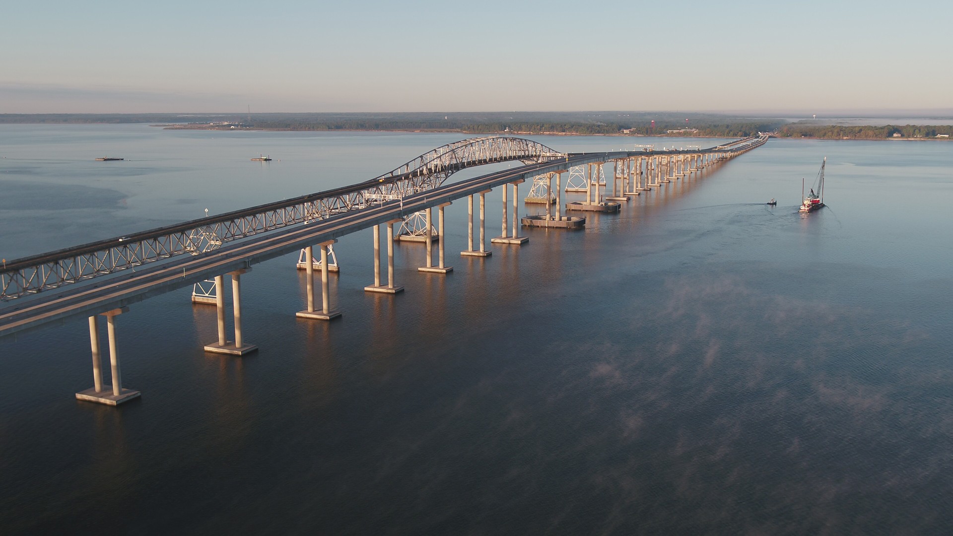 Sunrise View of Scenic Bridge Over Tranquil Waters Aerial view of the long, curving bridge over calm waters connecting two land masses.