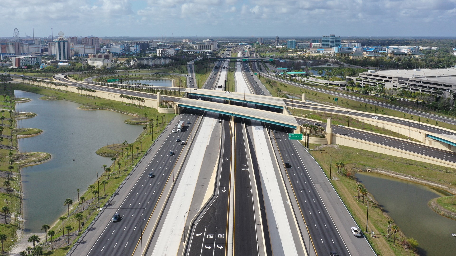 Modern Highway Infrastructure in Urban Landscape Aerial view of a modern highway intersection with surrounding urban landscape and water bodies.
