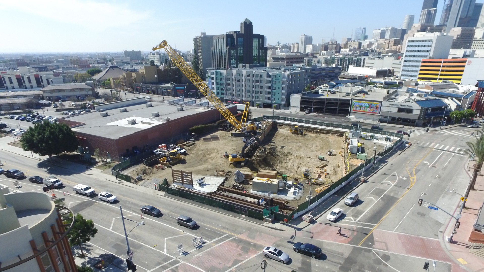 Construction site with crane in an urban area near busy city streets and buildings.
