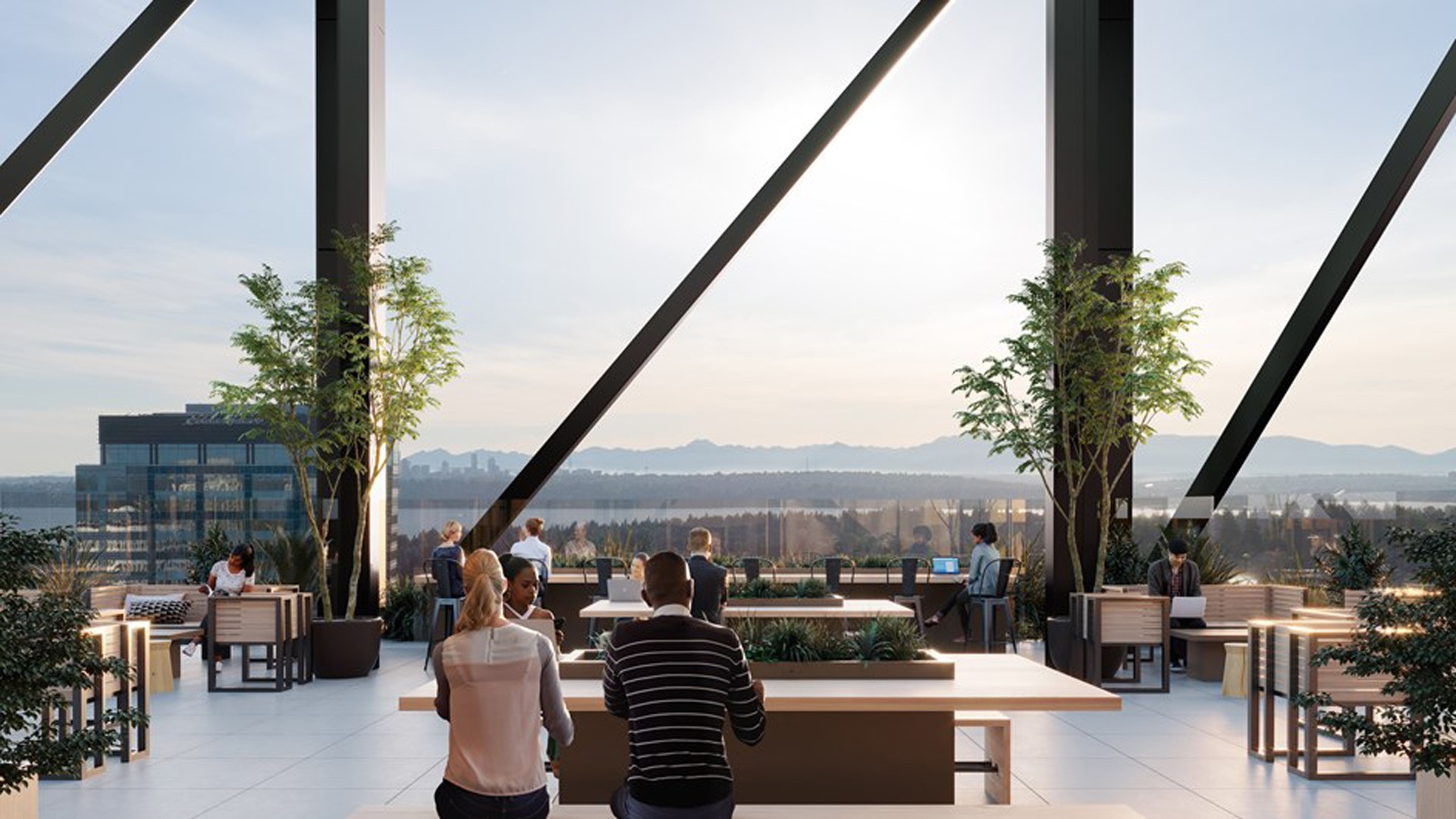 Modern rooftop workspace with city view and natural light People working and socializing on a modern rooftop terrace with city and mountain views.