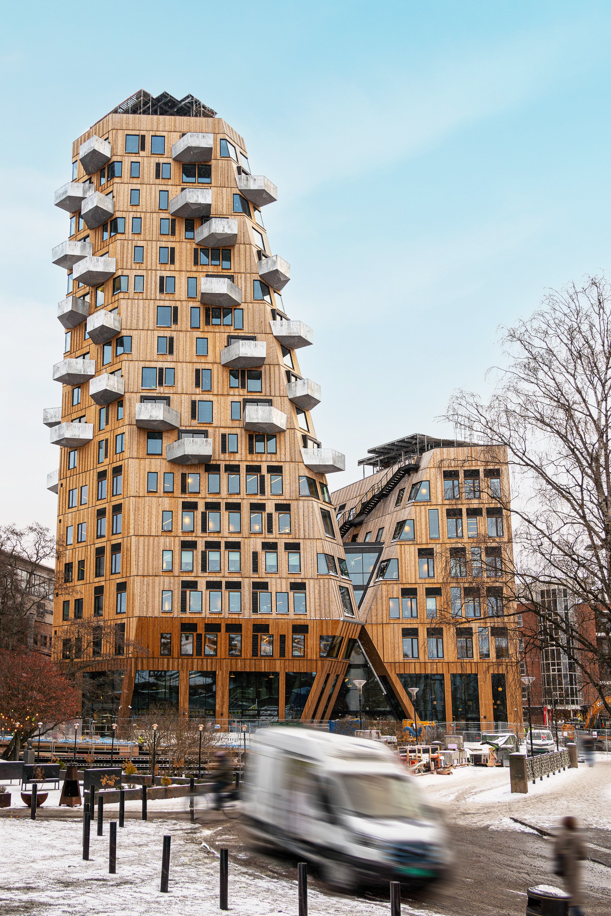 Gullhaug Torg 2A Futuristisk bygningskompleks med unik arkitektur ved siden av en kanal i en tåkete vinterlandskap.