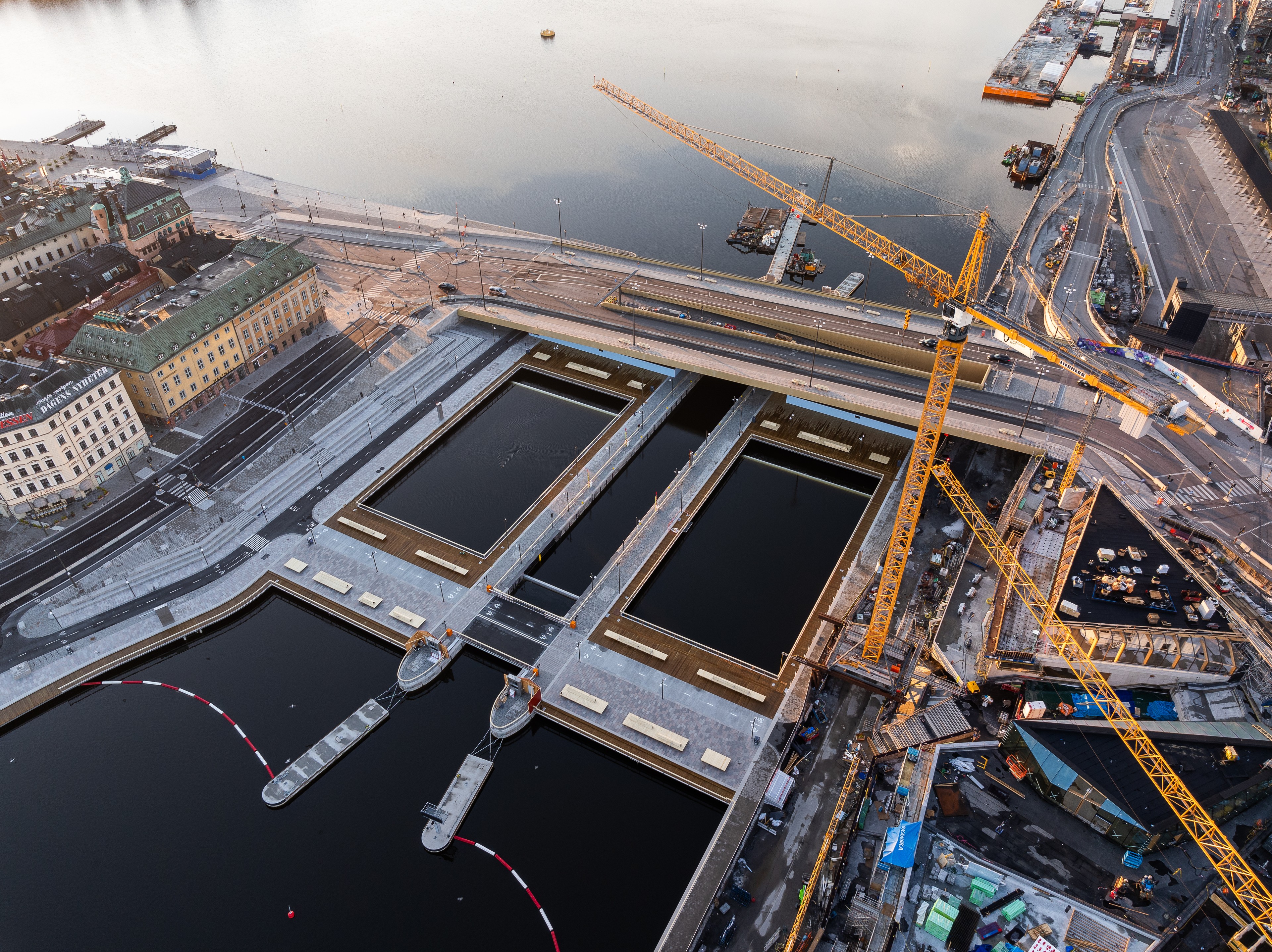 Aerial view of urban water canals under construction with cranes and surrounding buildings.
