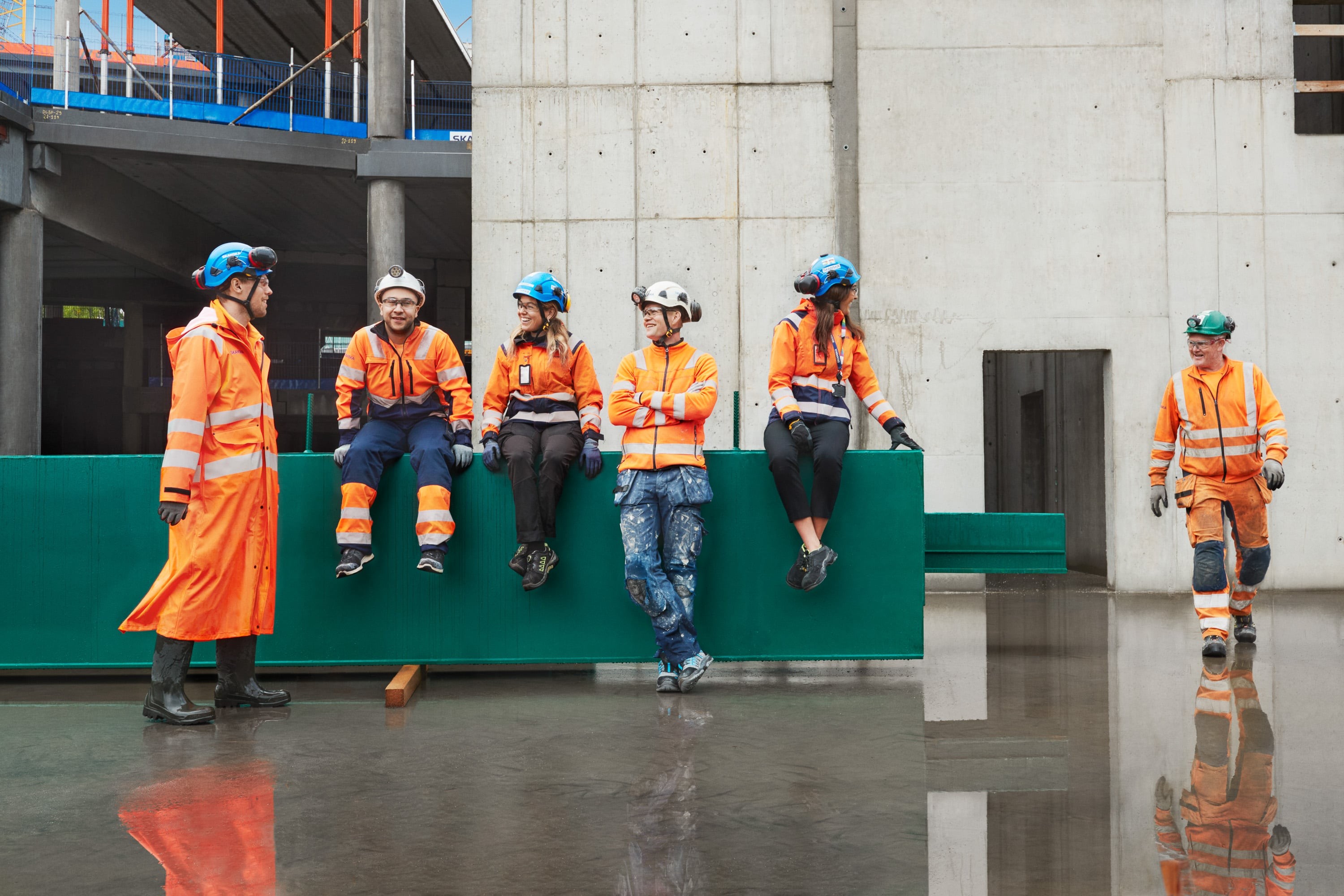 Construction workers in orange safety gear taking a break inside a modern building site.