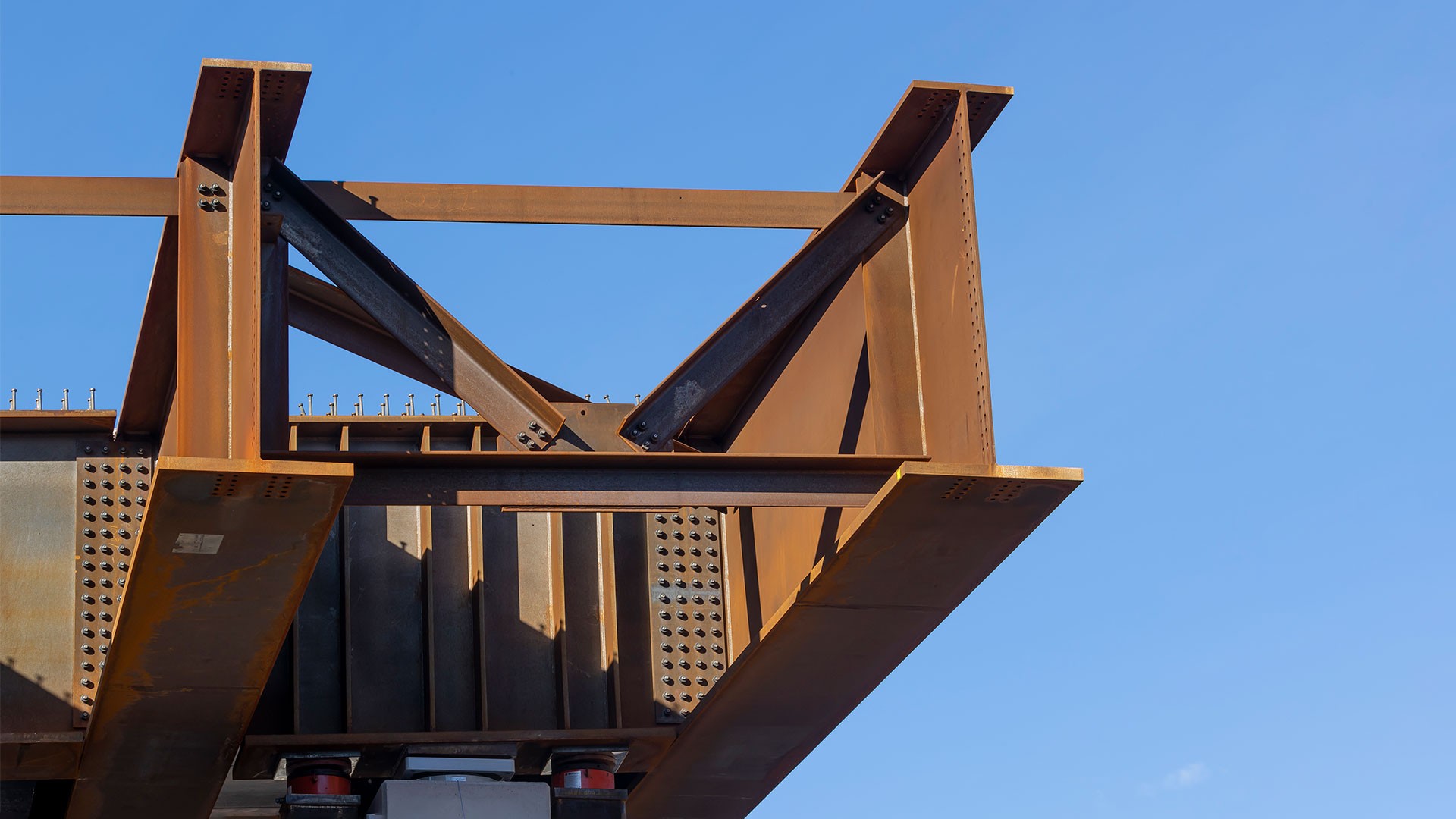 M42 Dual Bridge, Birmingham Close-up of a steel beam structure under blue sky, showcasing industrial construction elements.