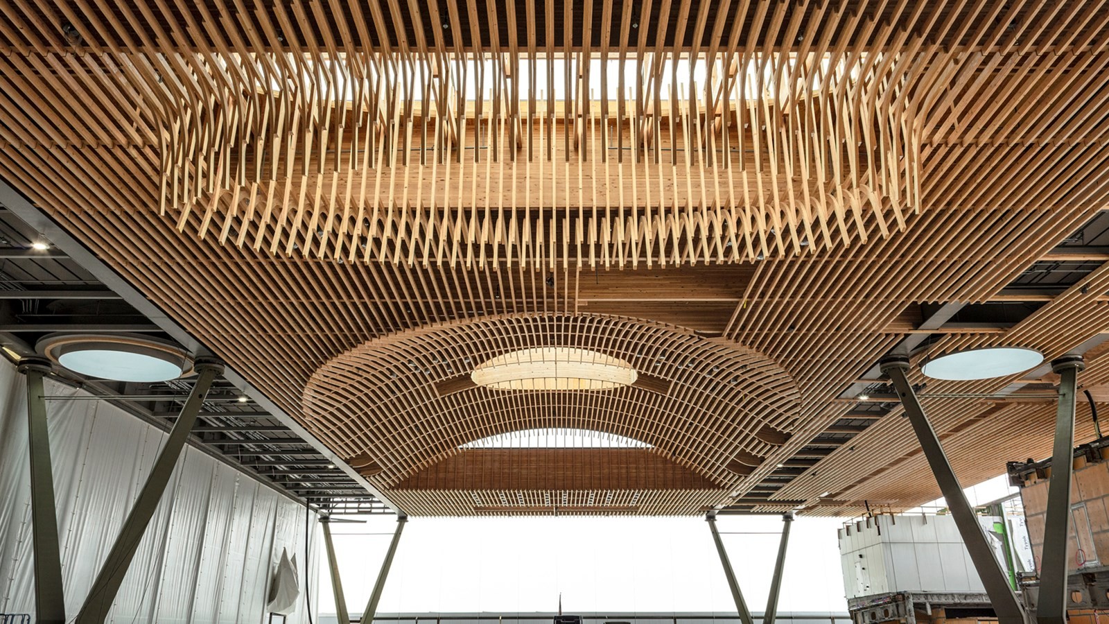 Wooden ceiling installation with intricate lattice design and circular skylight in a modern space.