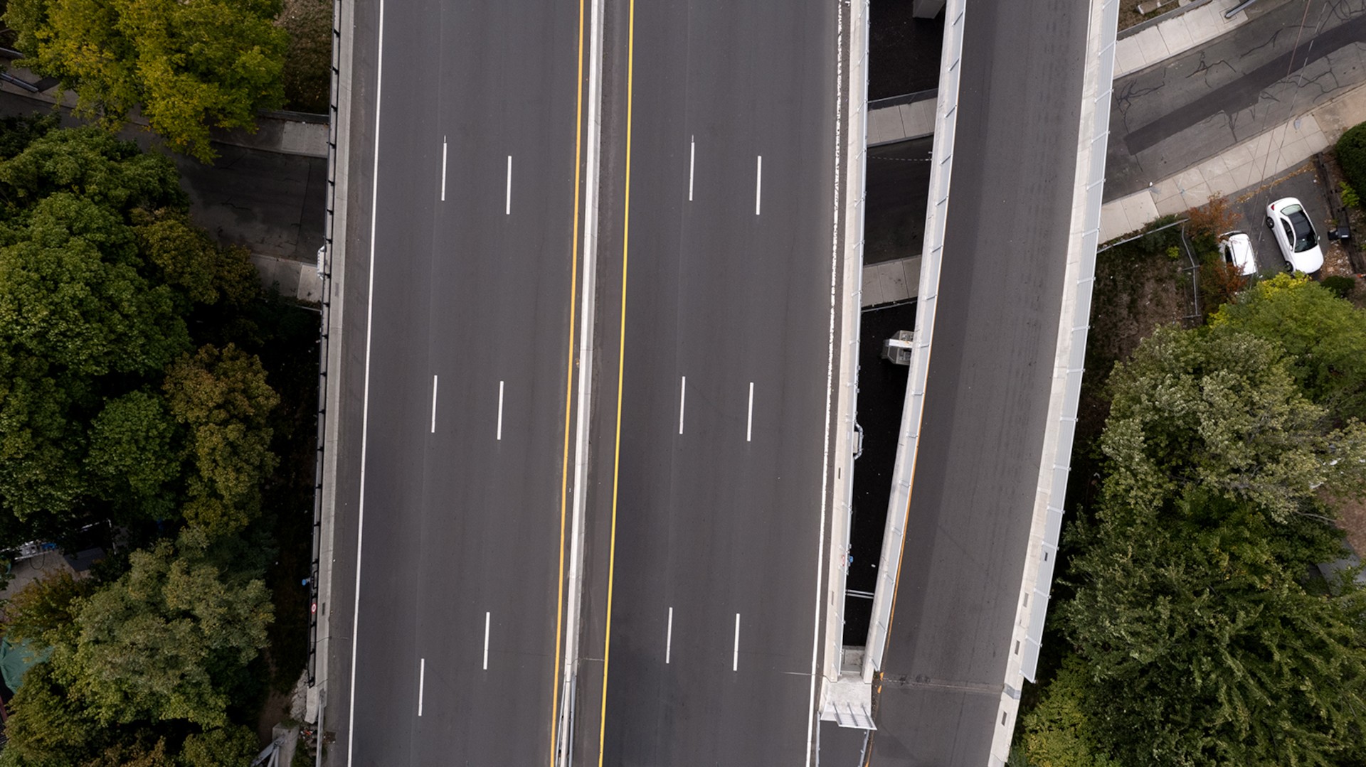 Aerial view of a multi-lane highway with surrounding greenery and adjacent roads.