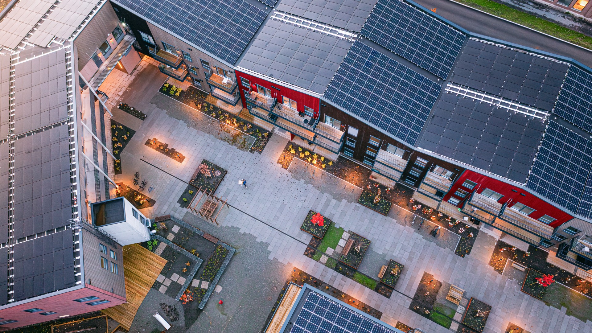 Aerial view of modern eco-friendly buildings with solar panels and landscaped courtyard.