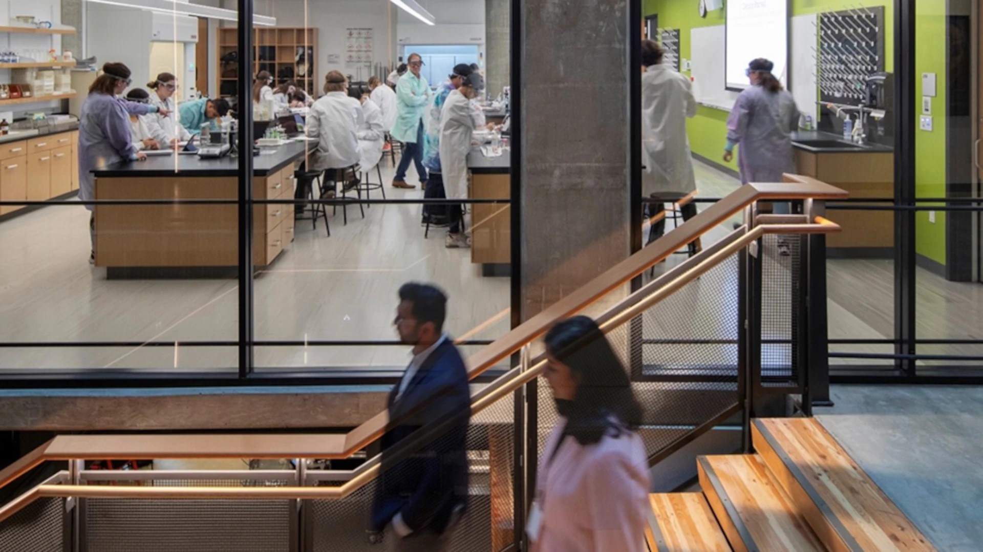 Modern Science Lab with Researchers and Transparent Design Modern laboratory setting with scientists in white coats working and discussing research projects.