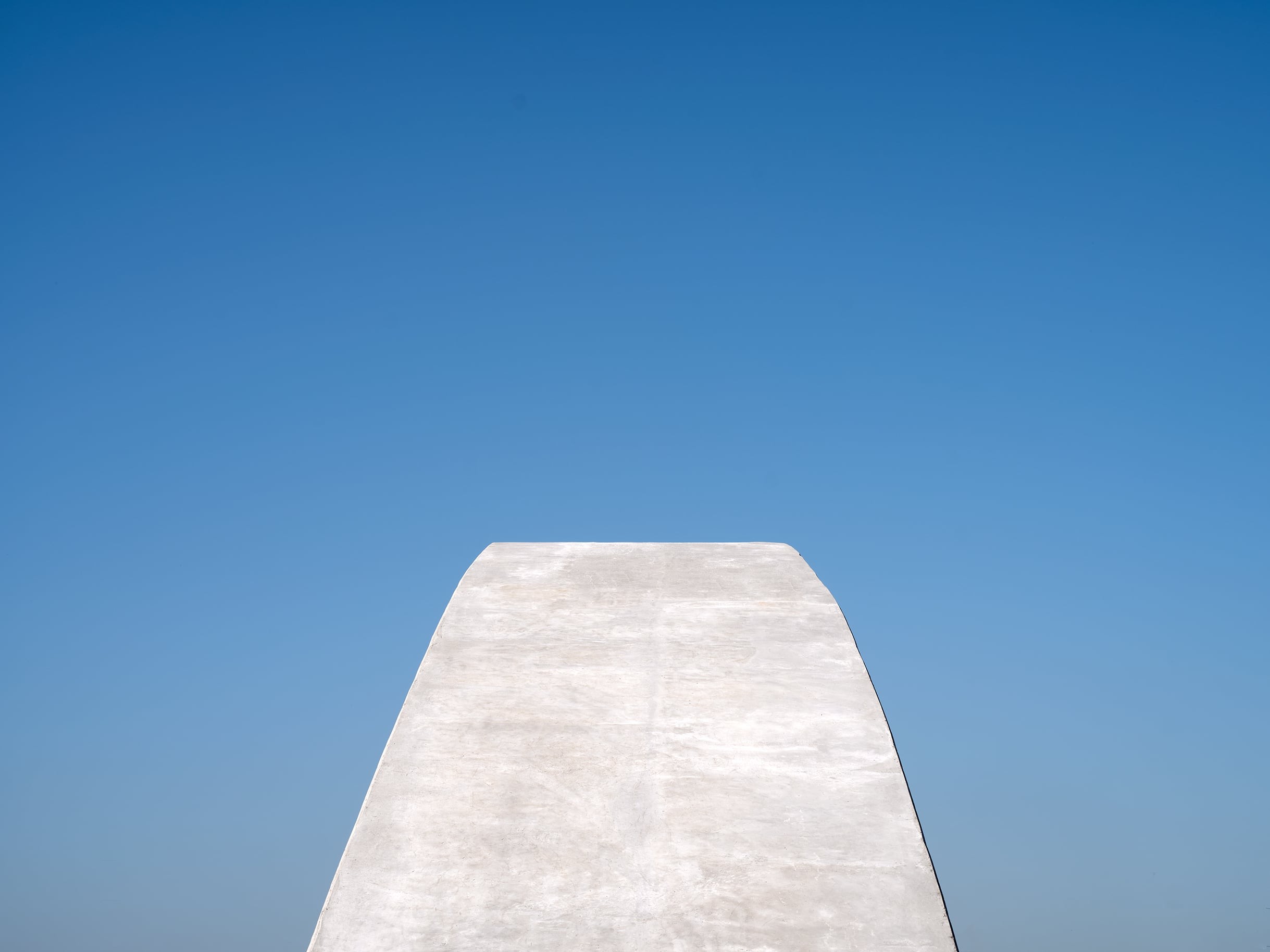 Betongstruktur mot en klar blå himmel, som visar minimalistisk arkitektur.