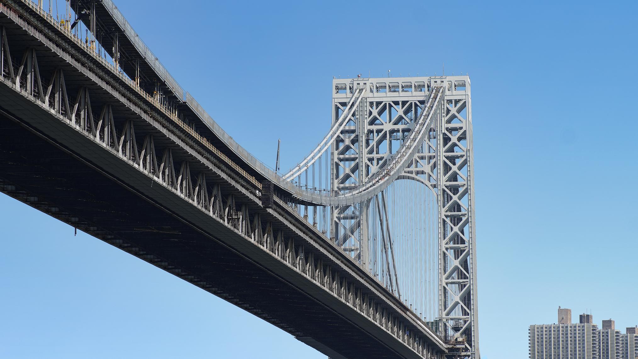 View of the George Washington Bridge against a clear blue sky with nearby buildings.