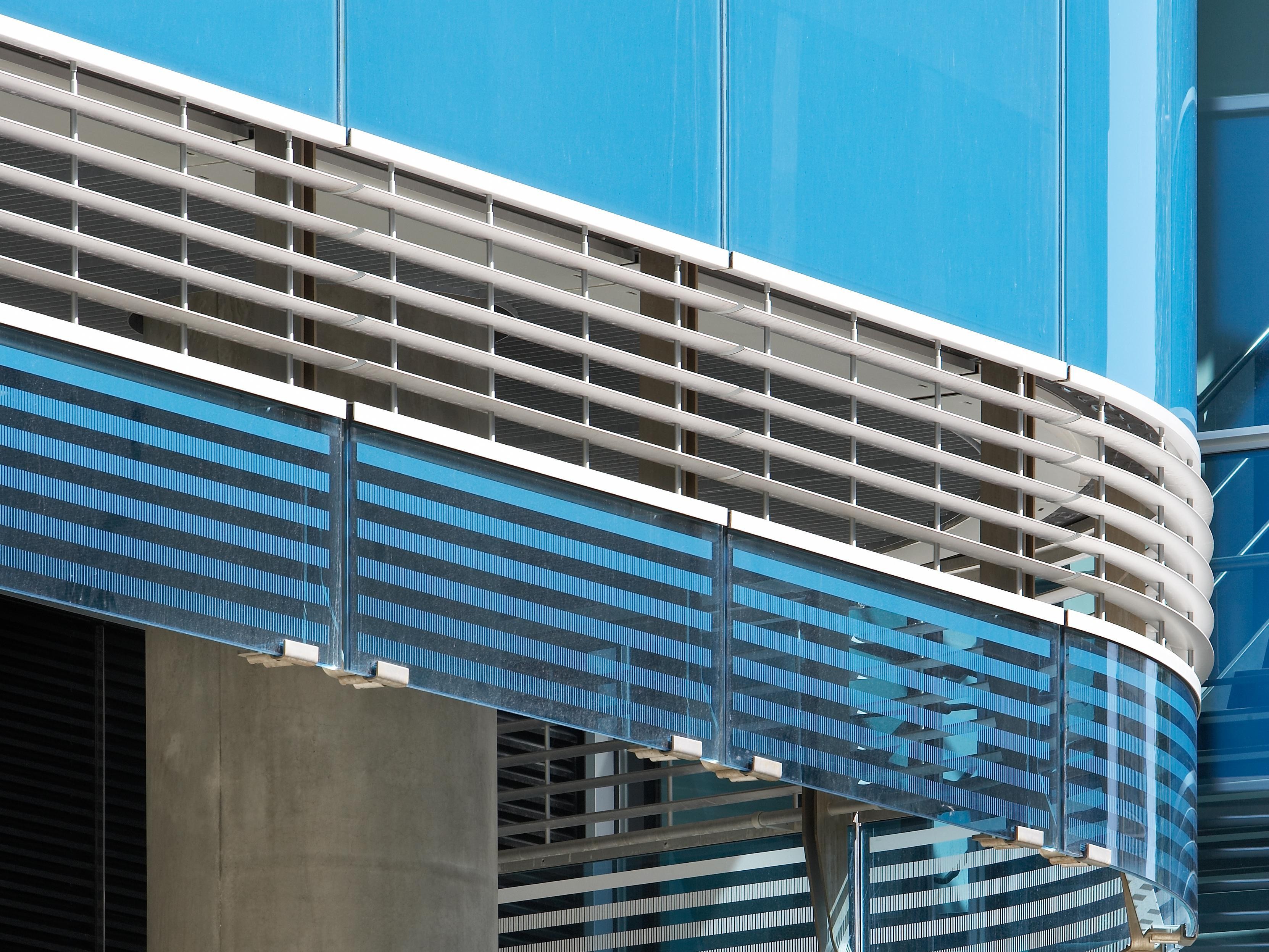 Modern building facade with blue glass panels and horizontal white slatted design elements.