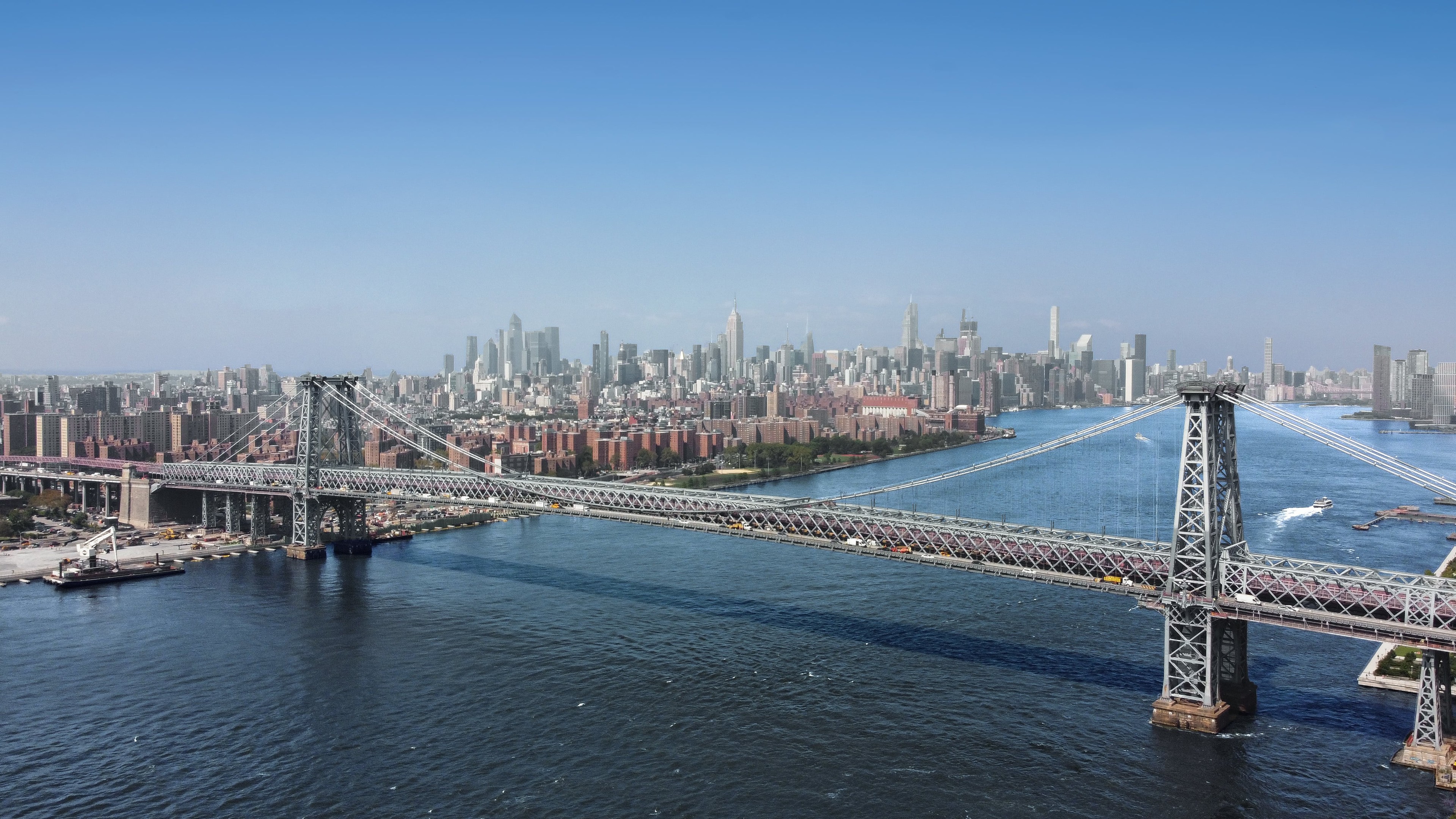 Panoramic view of the Williamsburg Bridge spanning the East River with NYC skyline.