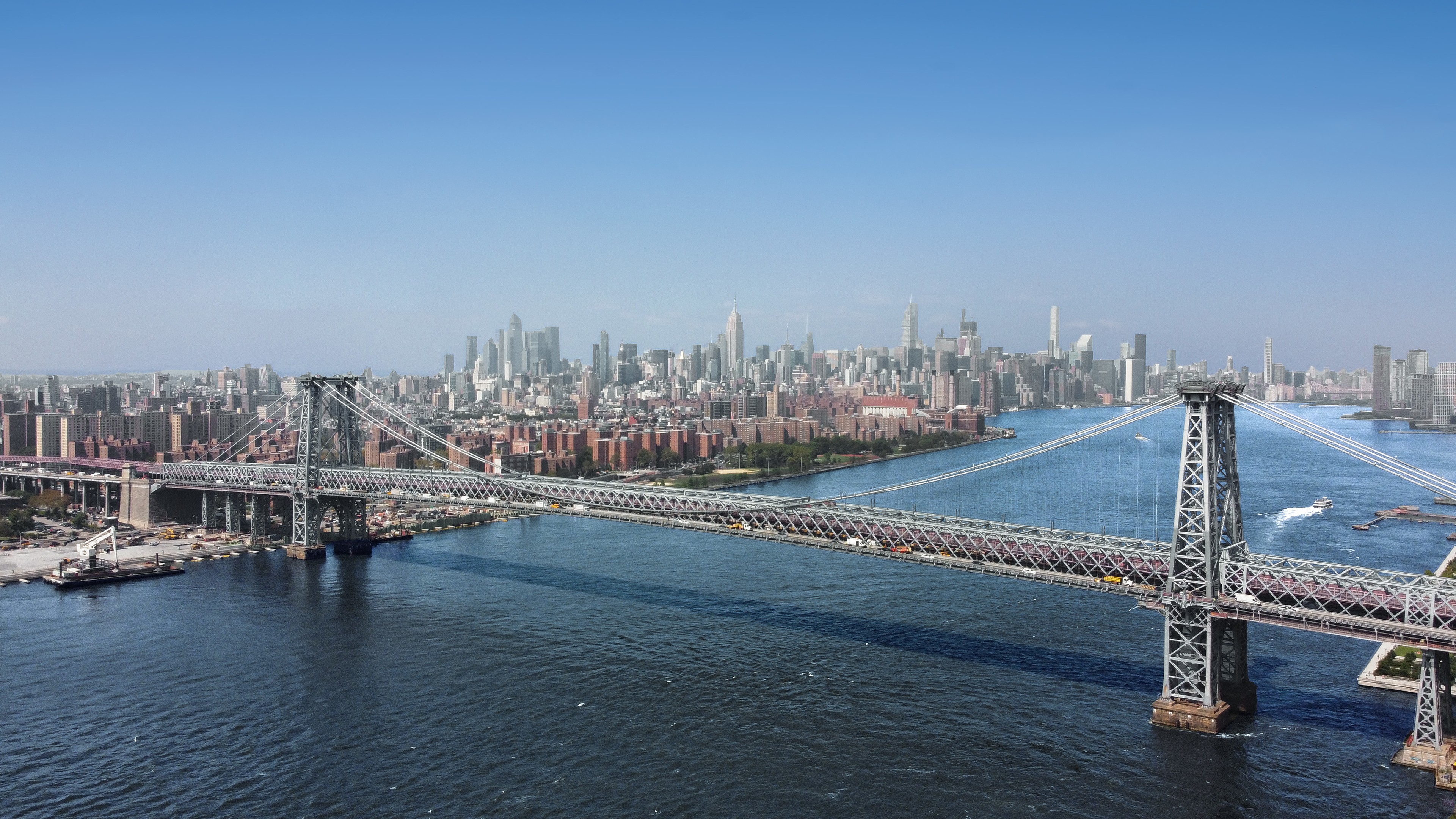 Panoramic view of the Williamsburg Bridge spanning the East River with NYC skyline.