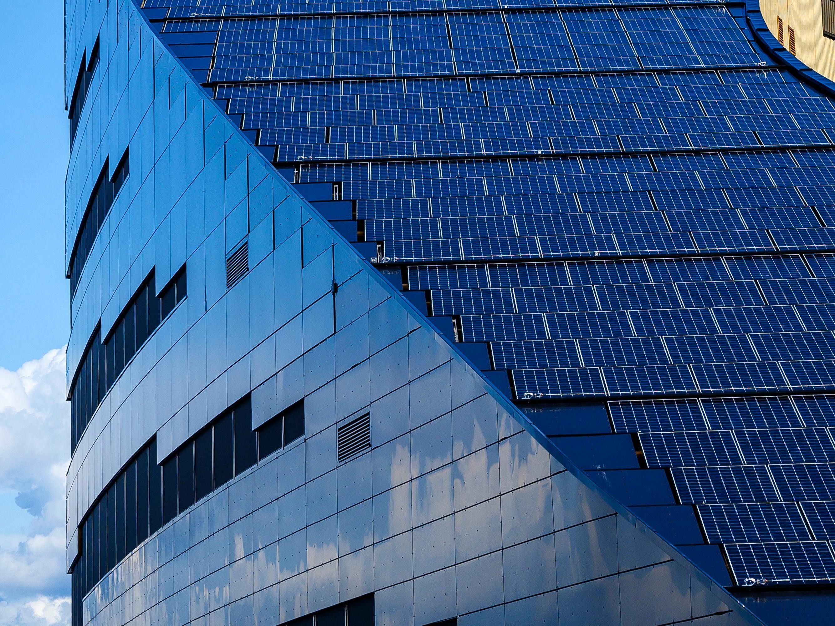 Close-up of modern building facade covered in blue solar panels, showcasing sustainable design.