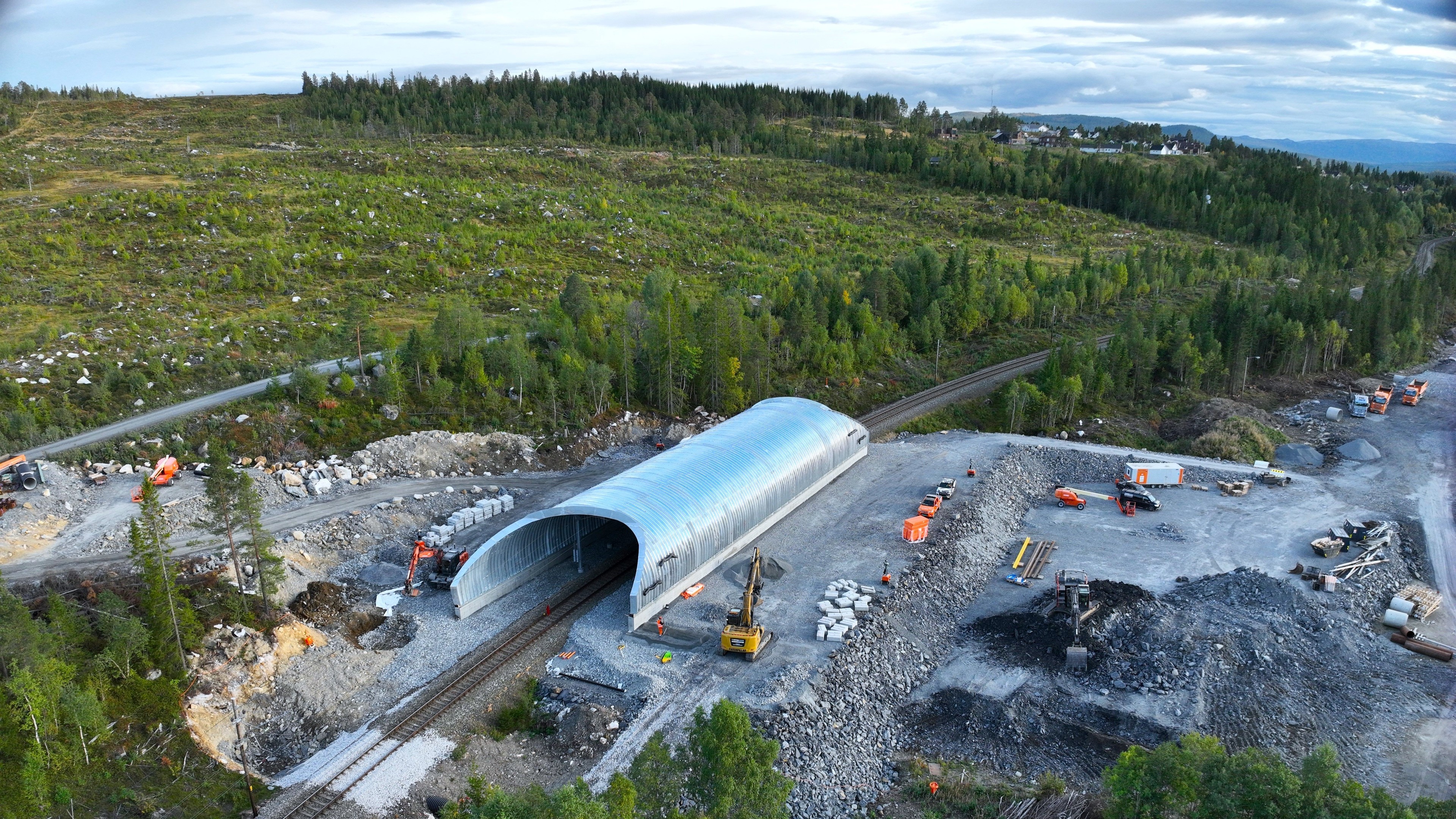 Construction of a metal-covered railway tunnel in a forested, rural area.