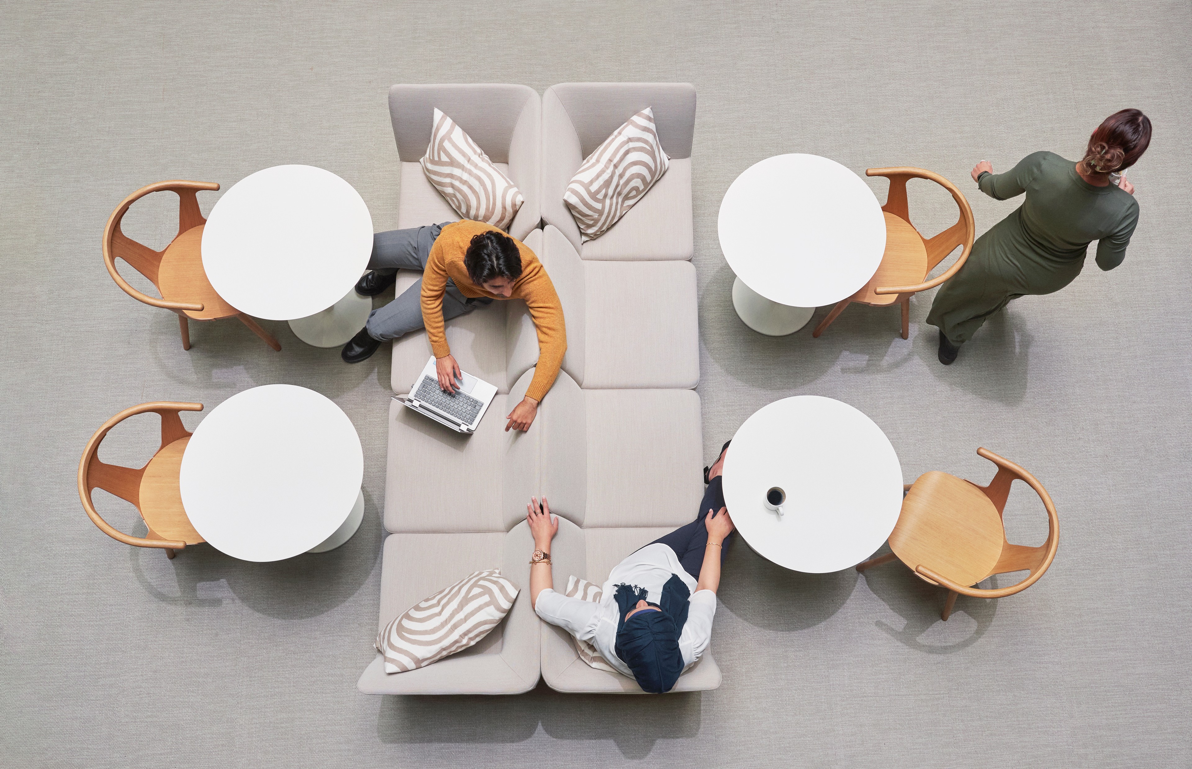 Modern Office Collaboration Space with People and Laptops Toppen utsikt av tre personer i et moderne loungeområde med bord, stoler og bærbare datamaskiner.