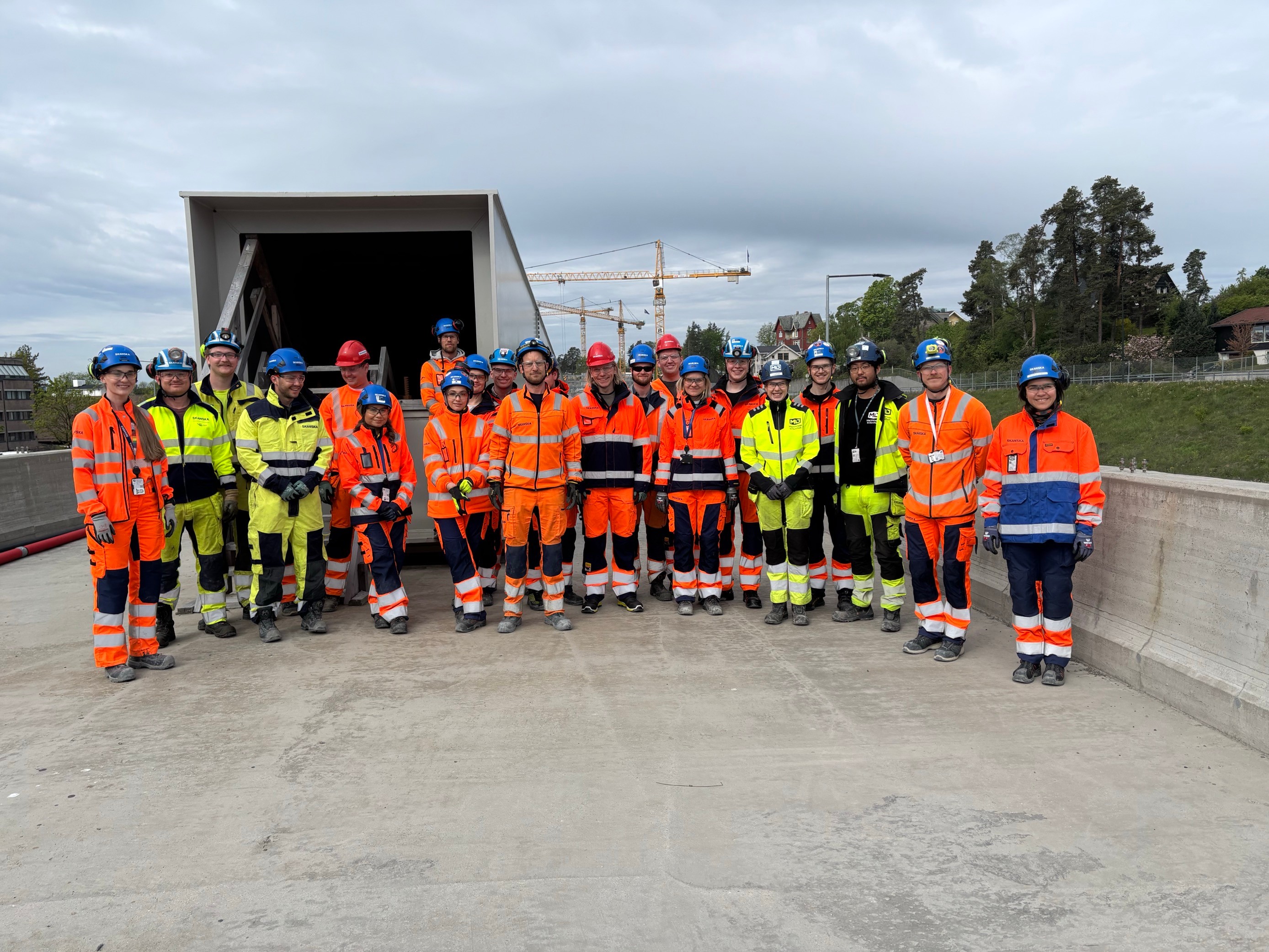 Construction workers team in safety gear at outdoor site Gruppe av byggherrer i høy synlighet sikkerhetsutstyr som står på en betongplass.