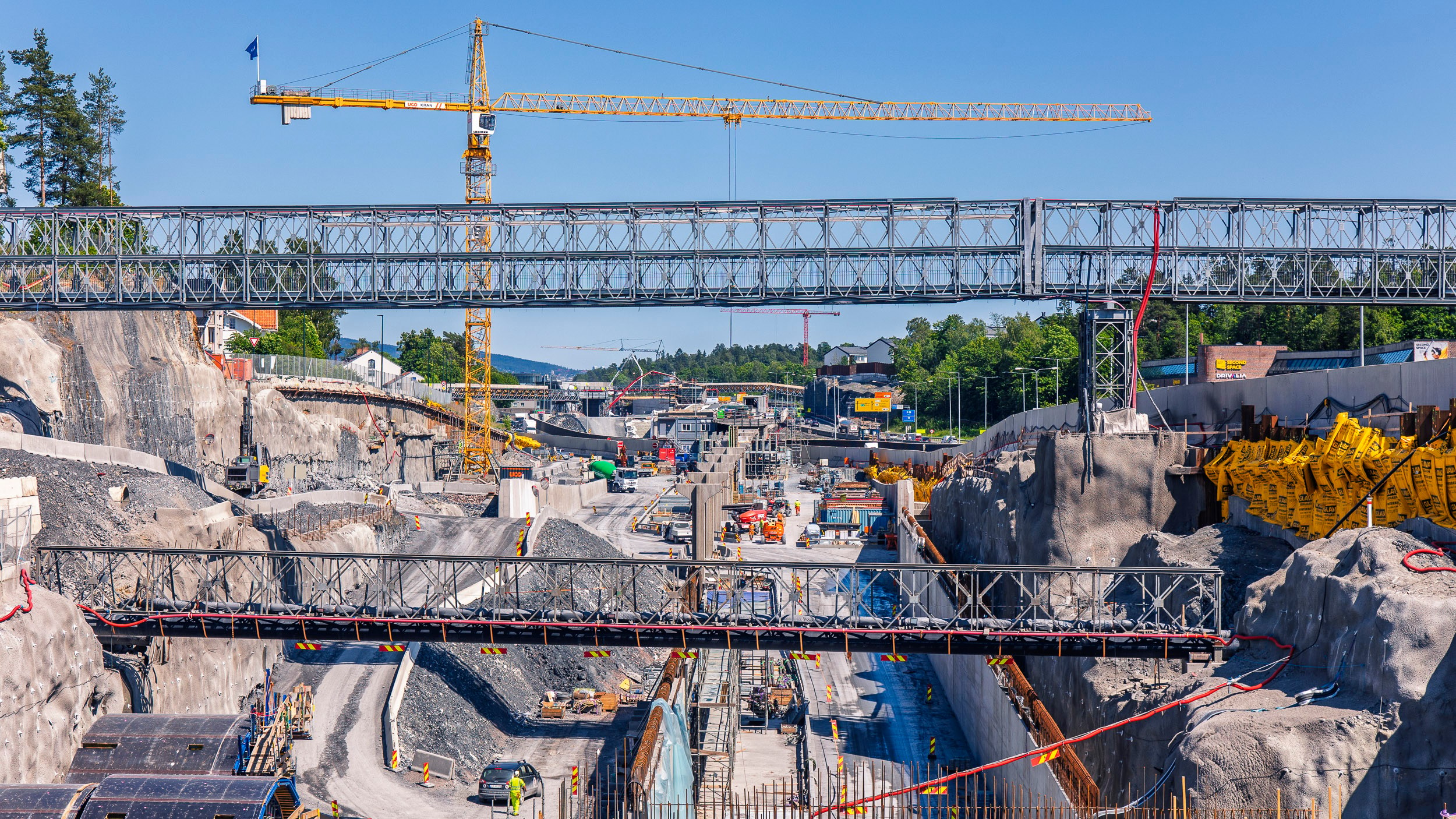 Highway Construction Site with Cranes and Bridges Stor byggeplass med kraner, midlertidige broer og arbeidere omgitt av steinete terreng.