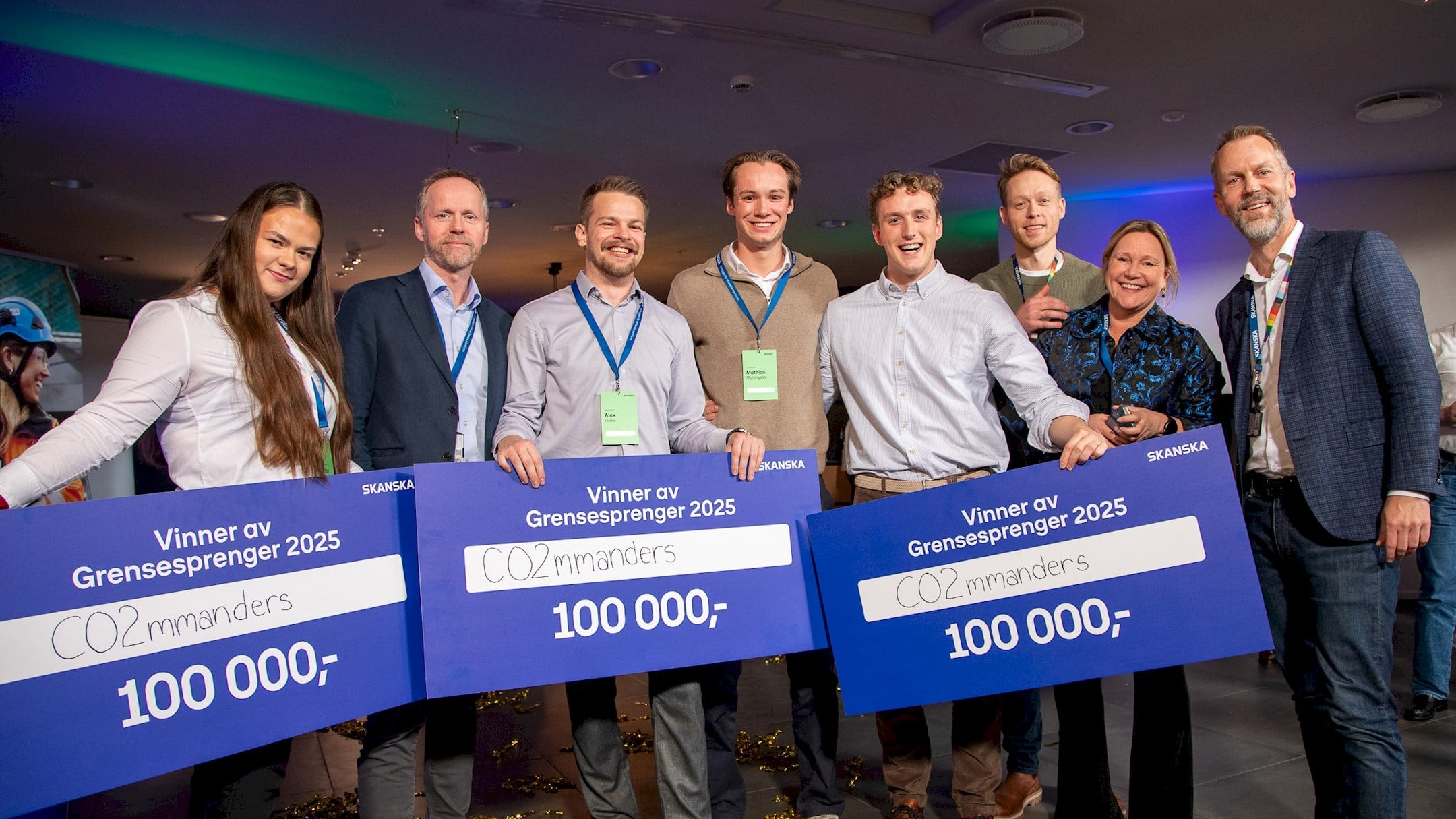 Gruppe mennesker som holder store sjekker for "Vinner av Grensesprenger 2025" med en premie på 100 000.