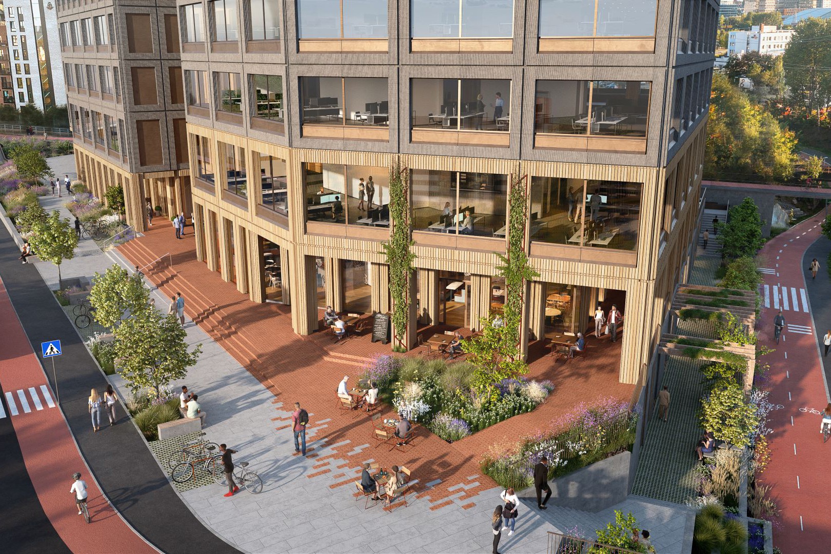 Moderne kontorbygning med store vinduer, utendørs sitteplasser og anlagt fotgjengerområde.