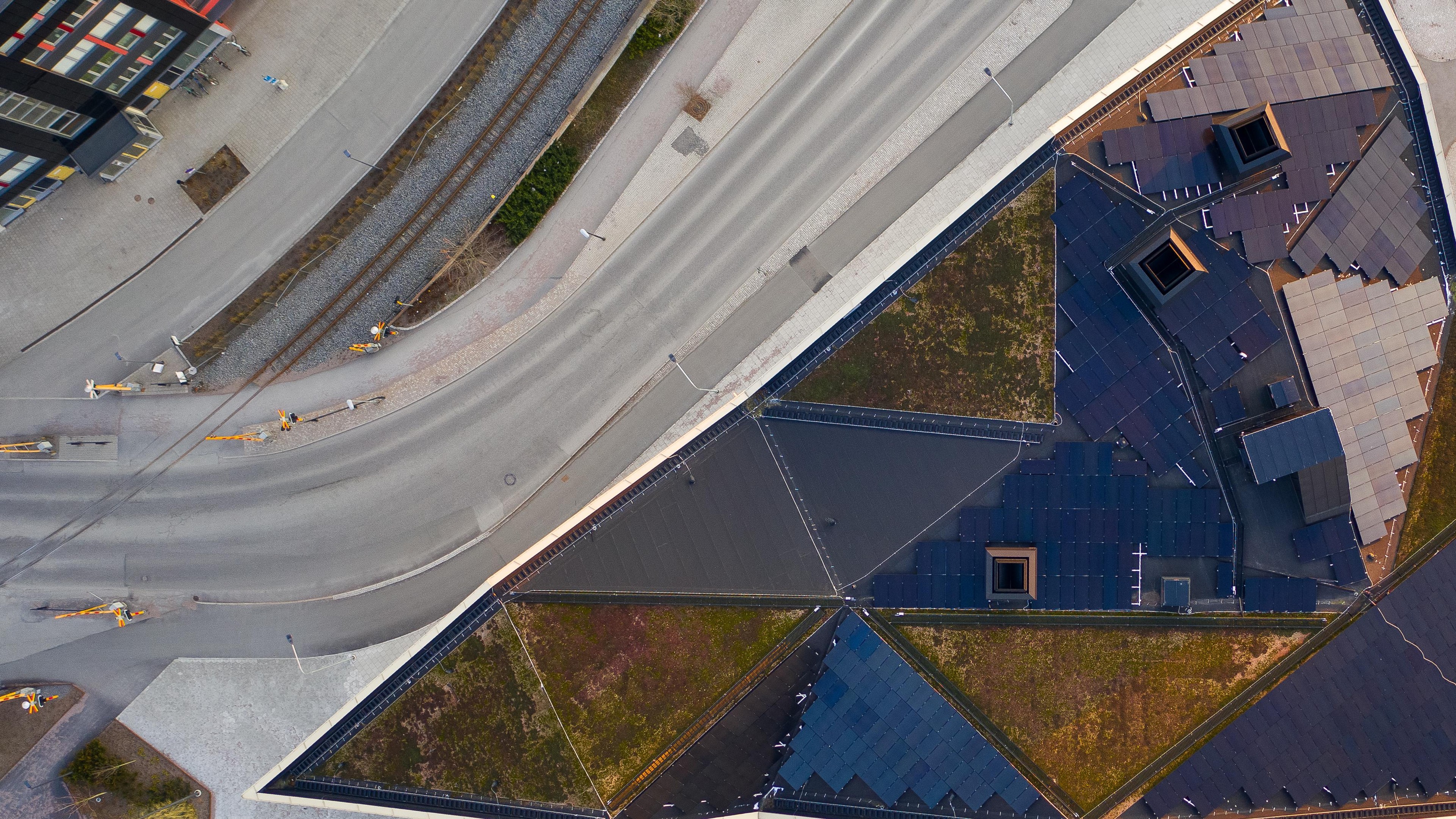 Flygfoto av geometrisk takträdgård med järnväg och väg intill i stadsområde.