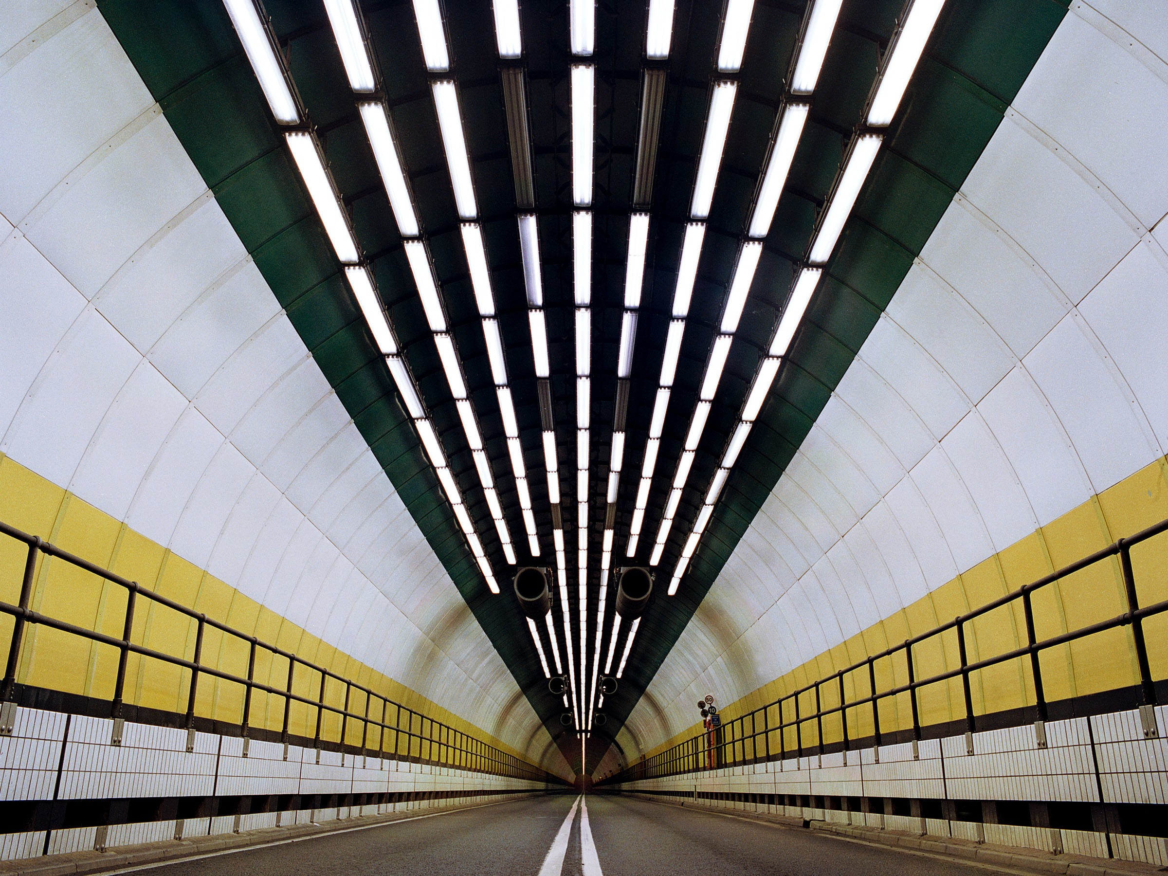 Gruvutrustning under jord i aktion: Tunnelgrävning Grävmaskin upplyst i en svagt upplyst underjordisk tunnel, omgiven av steniga väggar.