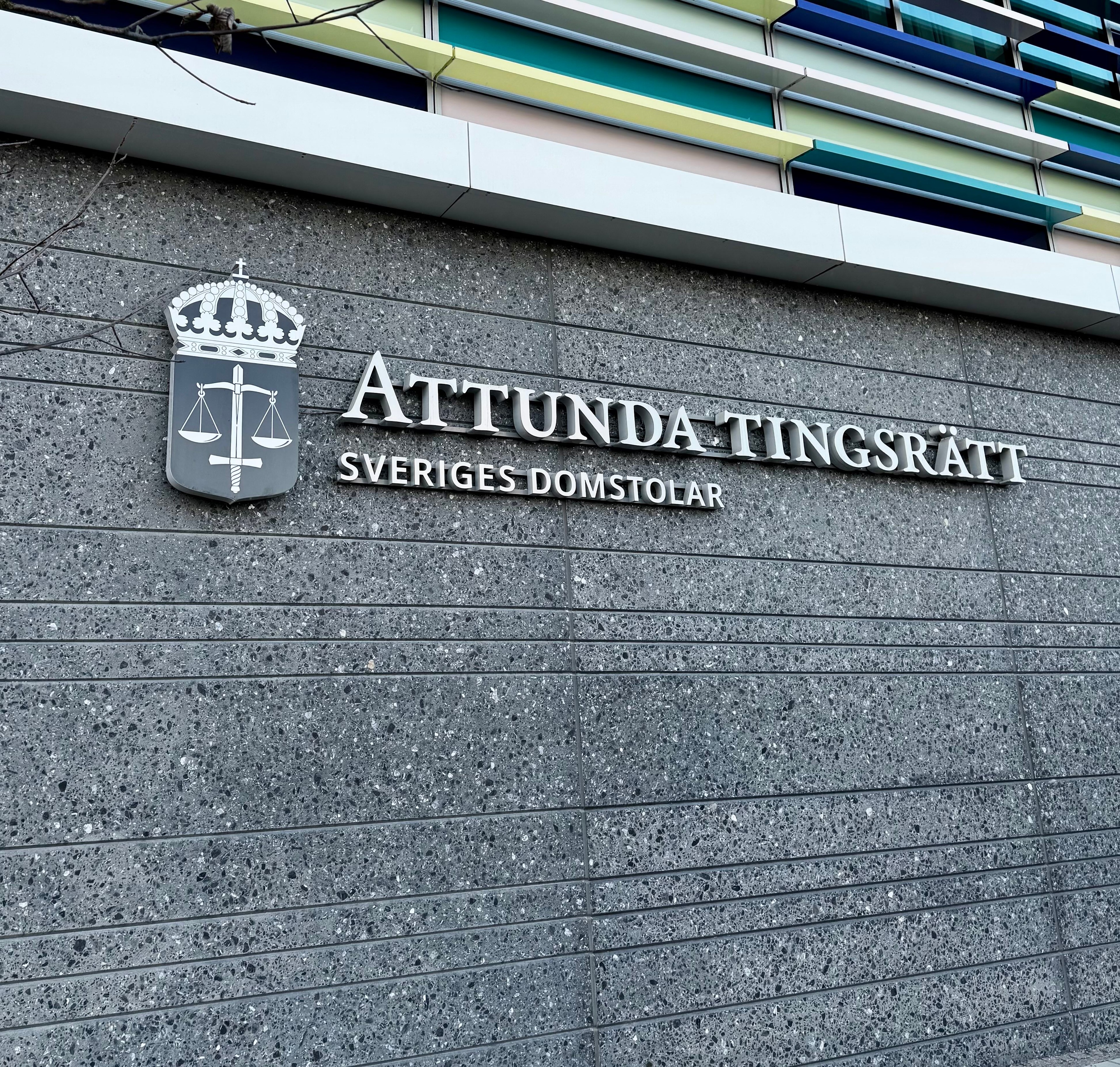 Skylt för Attunda tingsrätt, en del av det svenska rättsväsendet, på en strukturerad stenmur.