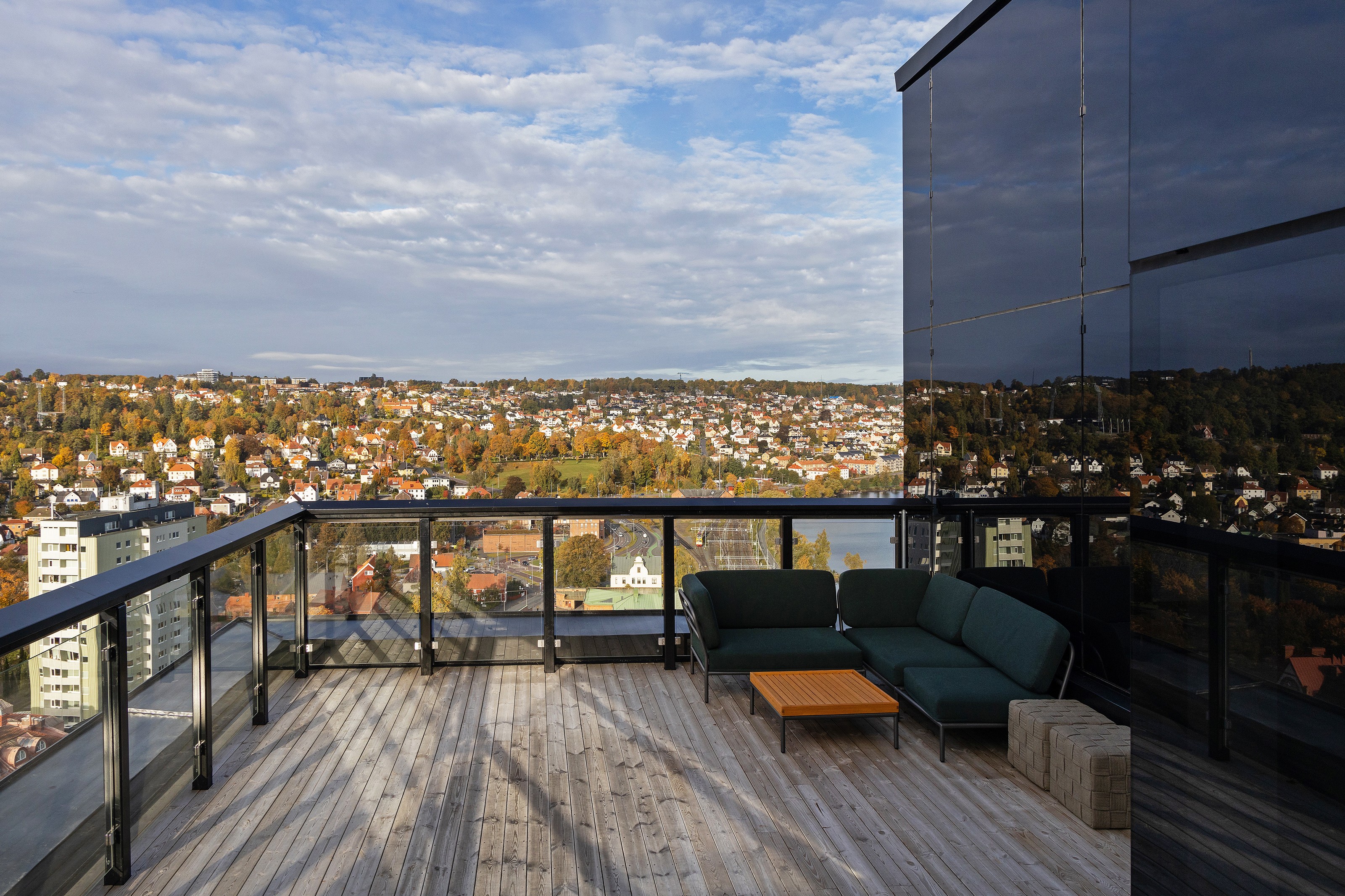 Rymlig takterrass med moderna utomhusmöbler och stadssilhuett under blå himmel.