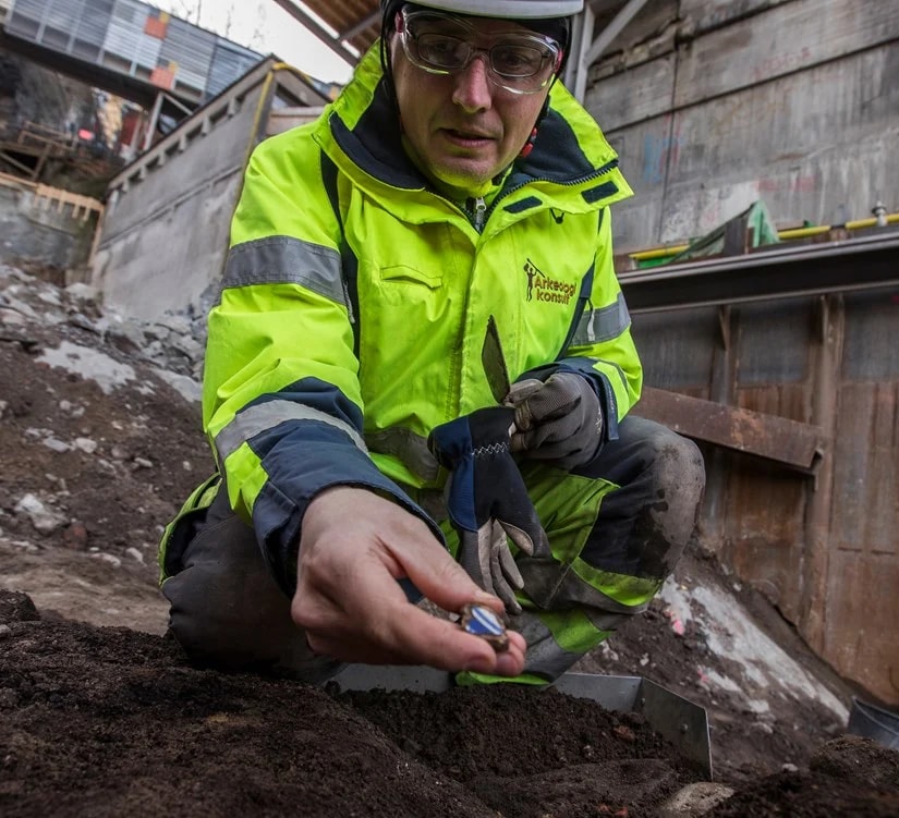 Byggarbetsplats framför färgglada urbana byggnader under en mulen himmel.