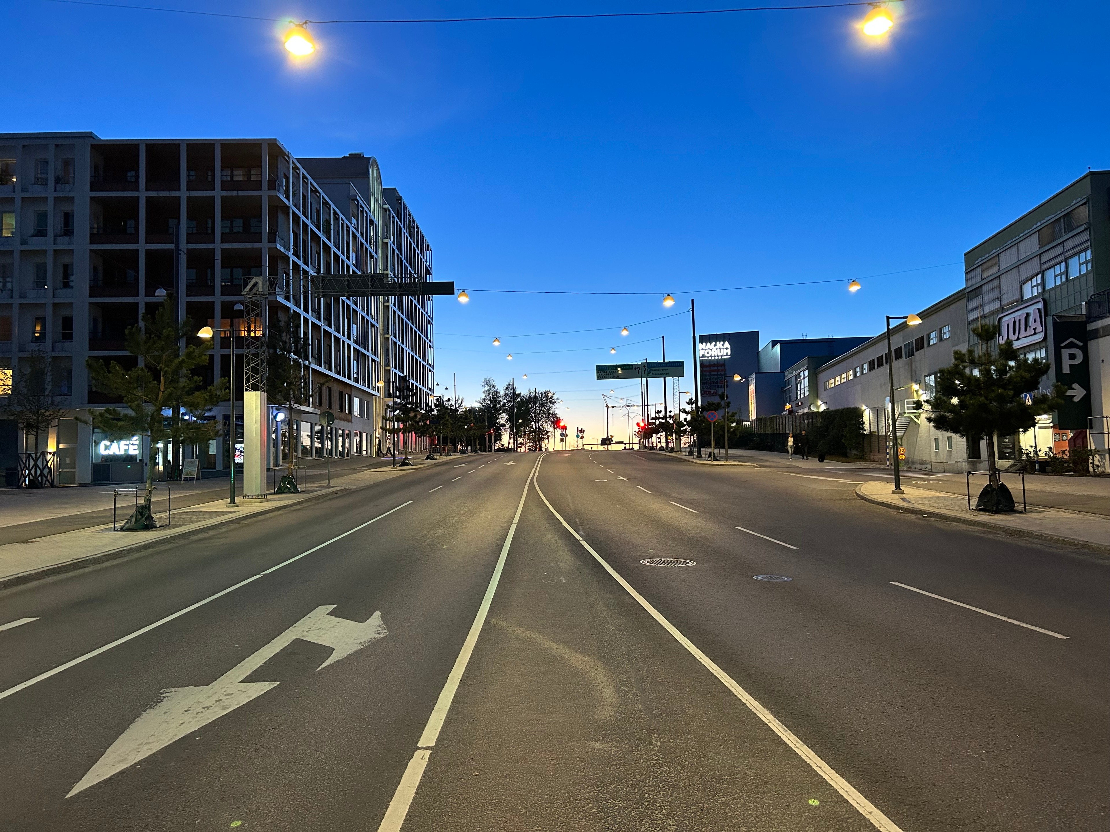 Tom urban gata i skymningen med moderna byggnader och gatlyktor under en klar himmel.