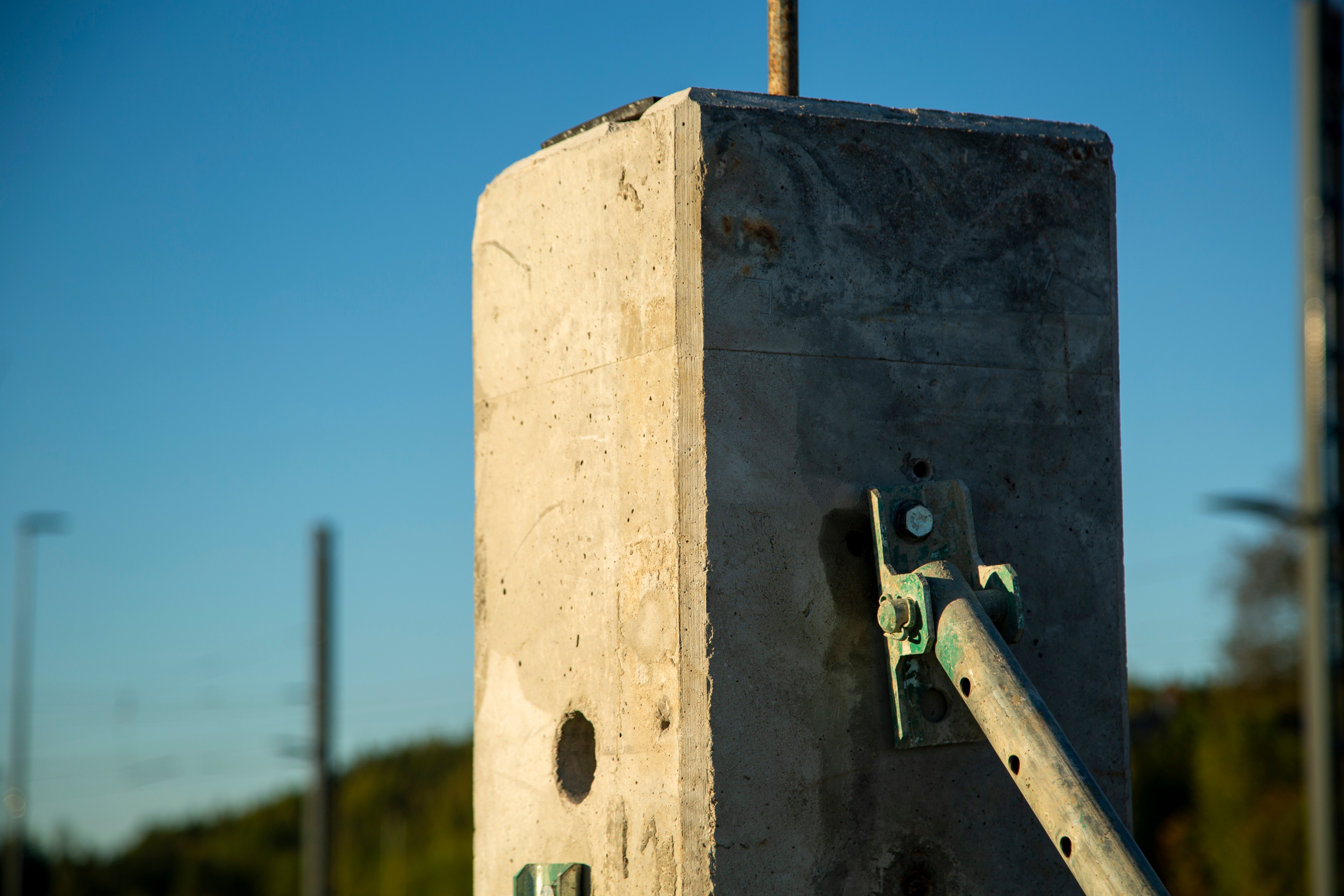 Concrete pillars with metal support at construction site Concrete pillar with metal bracket against a clear blue sky, placed on a construction site.