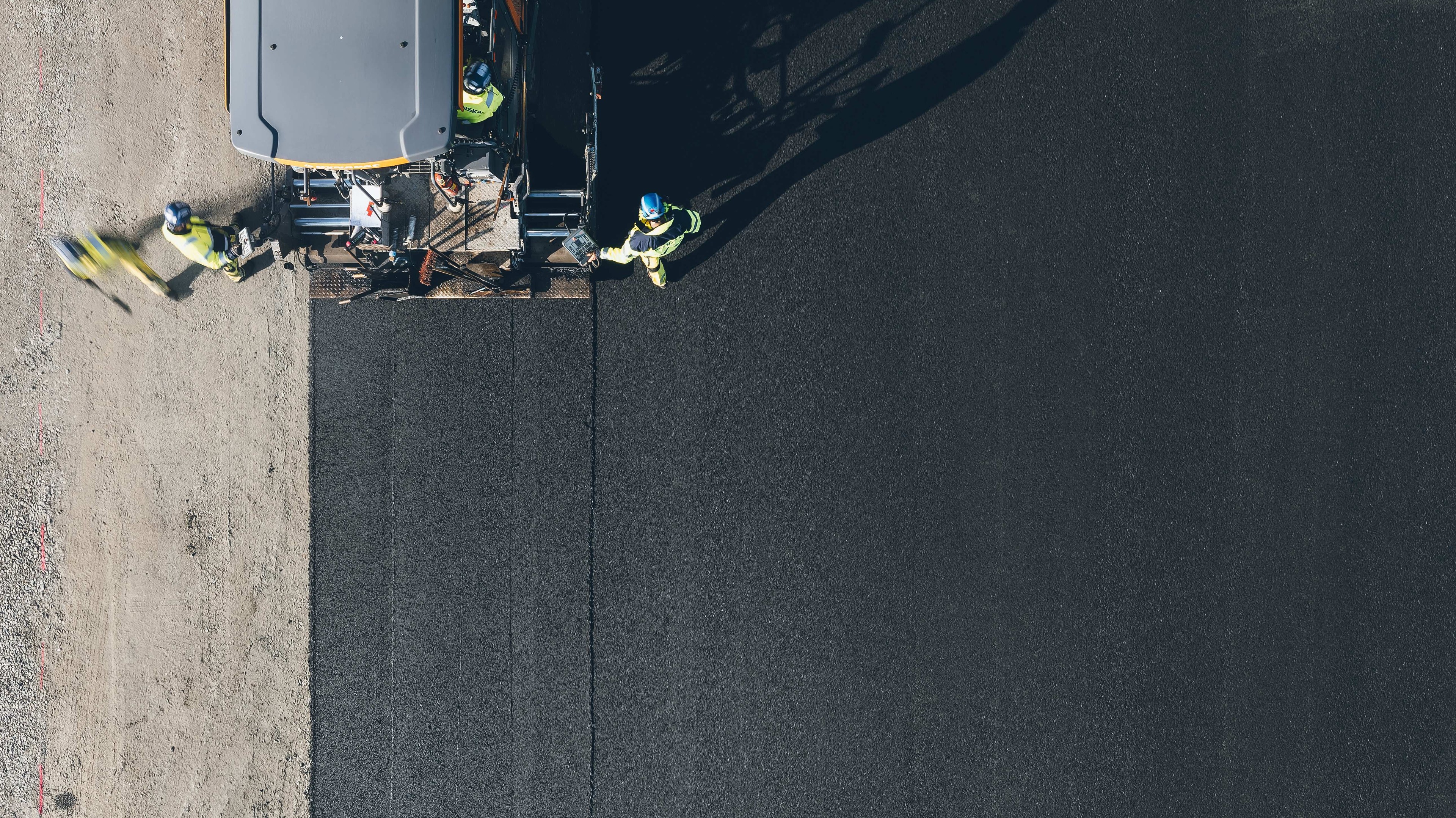 Roadwork: Asphalt paving in progress View from above Aerial view of workers paving a road with machines, creating a smooth asphalt surface.