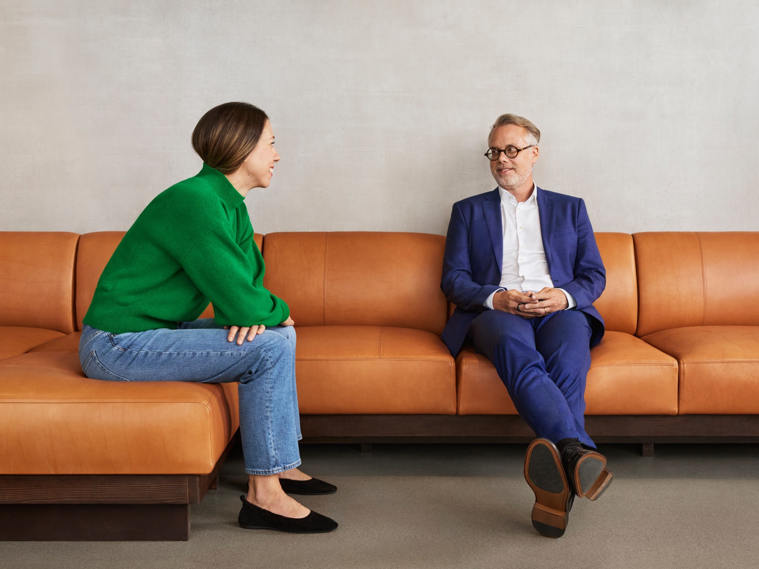 Professionell man och kvinna som har ett möte på soffa Två personer sitter i en soffa och samtalar