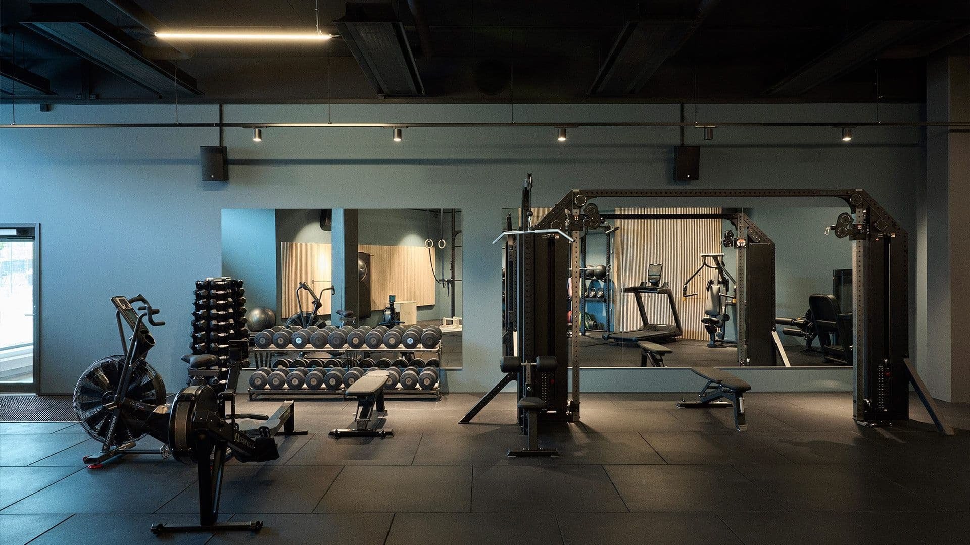 Modern gyminteriör med vikter, träningsmaskiner och stora speglar på väggarna.