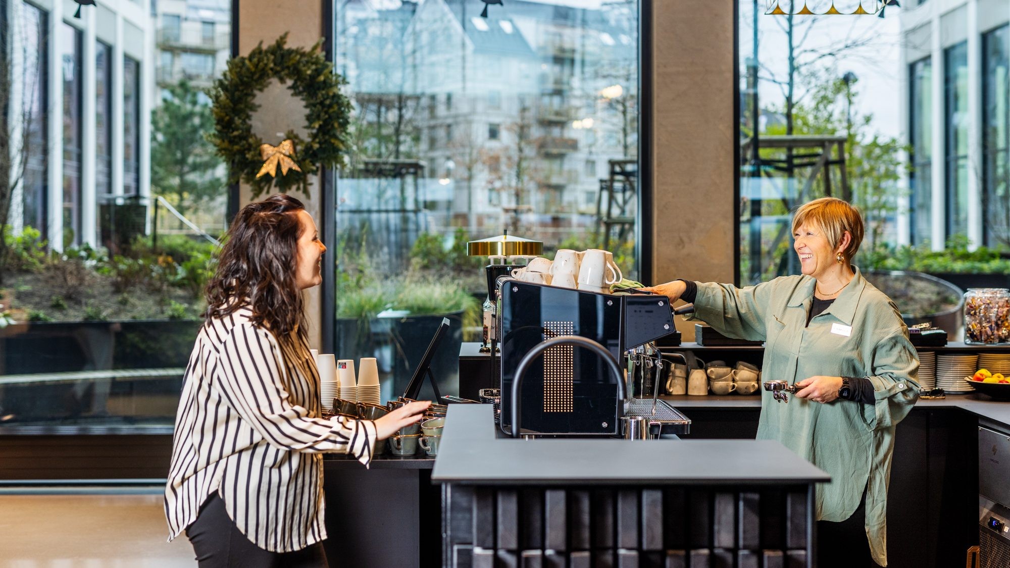 Modern kaféinteriör med barista och kundinteraktion Två personer i ett modernt café, med en barista som förbereder drycker bakom disken.