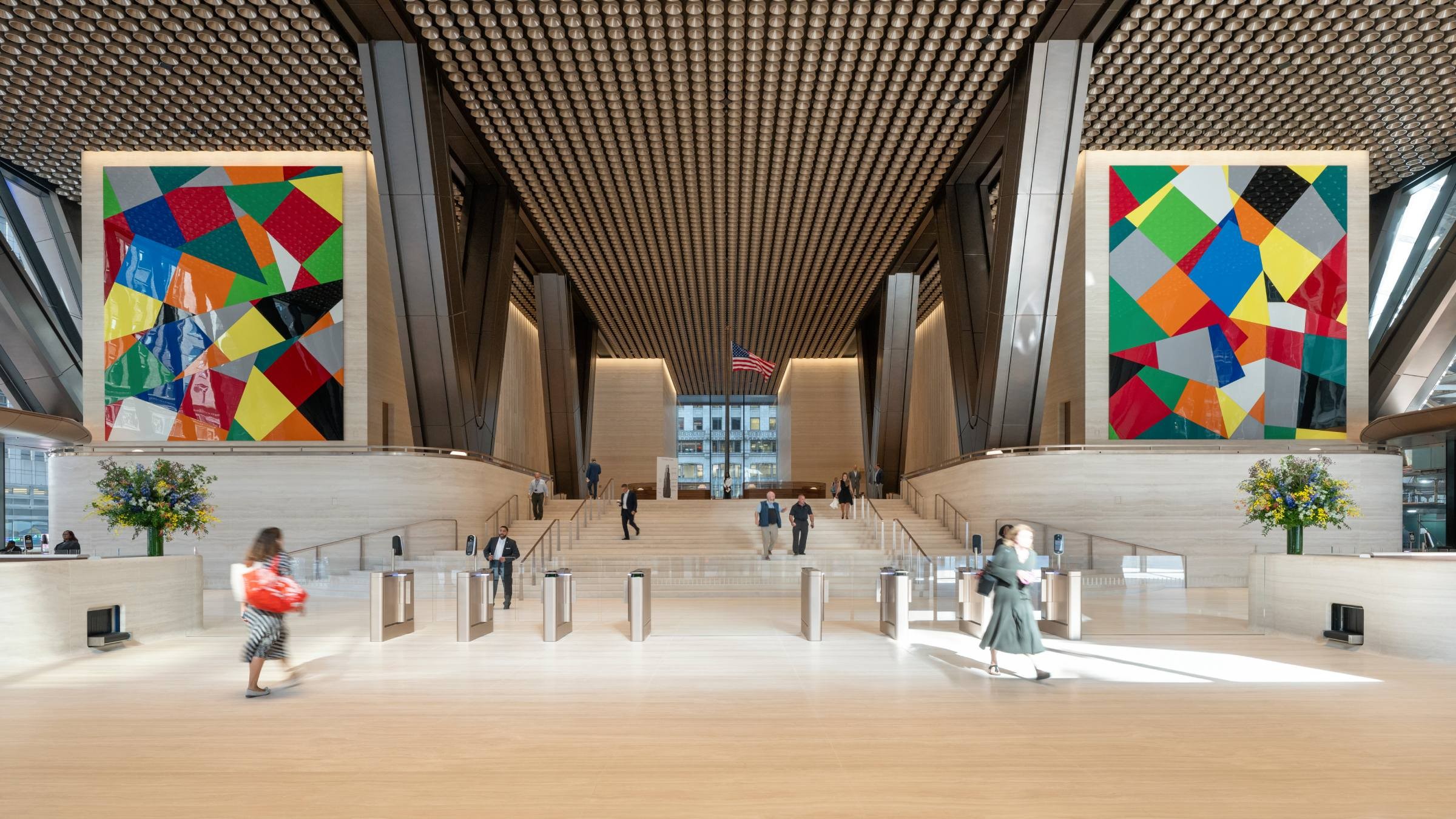 Rymlig modern lobby med färgstark abstrakt konst, träpanel i taket och människor som går.
