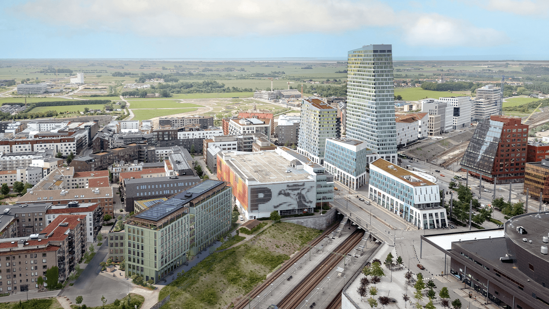 Flygvy över en modern stadsbild med höghus och öppna gröna ytor.
