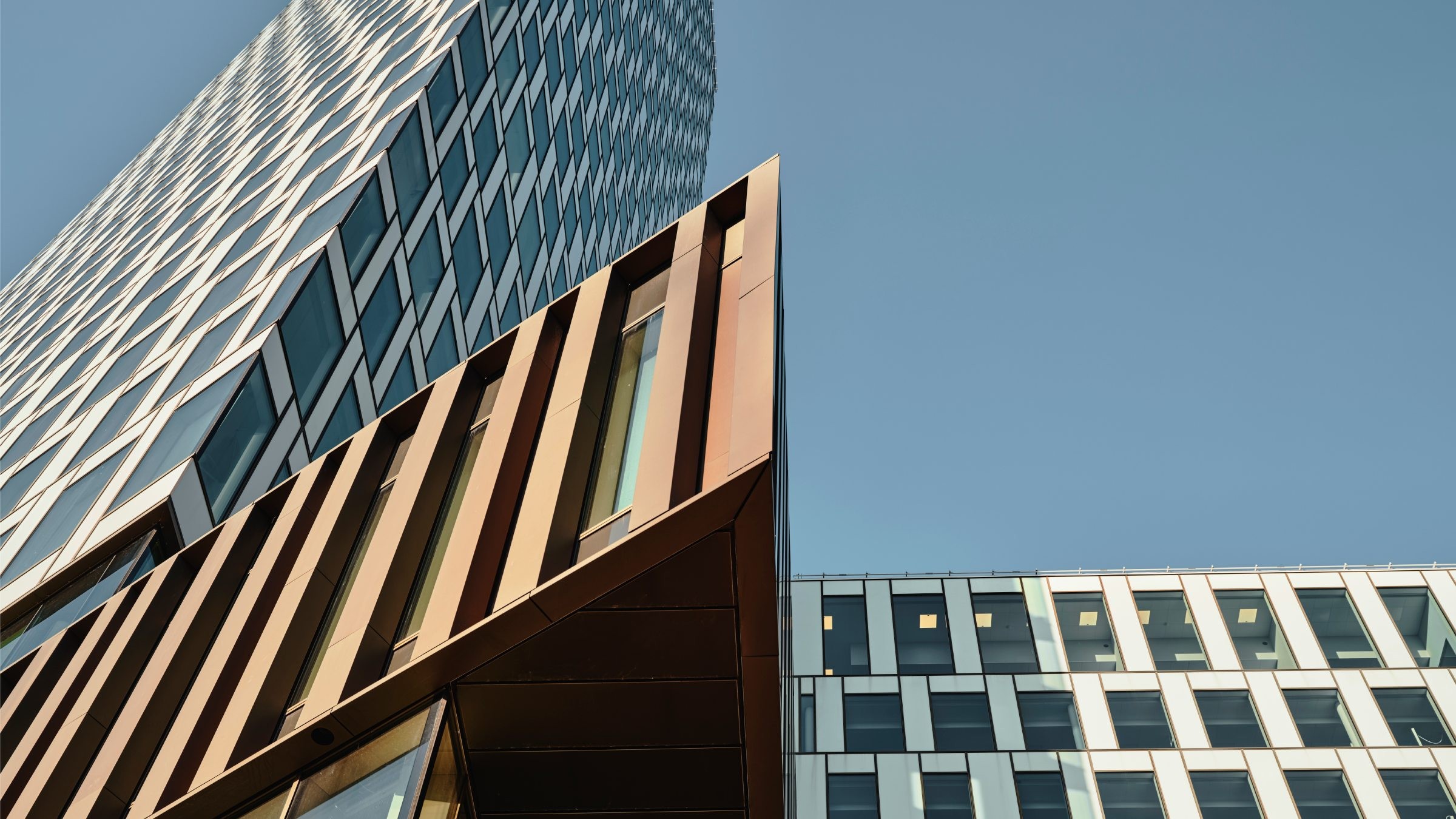 Modern arkitektonisk design: Snygga glas- och metallfasader Moderna skyskrapor med geometriska glas- och metallkonstruktioner under en klarblå himmel.