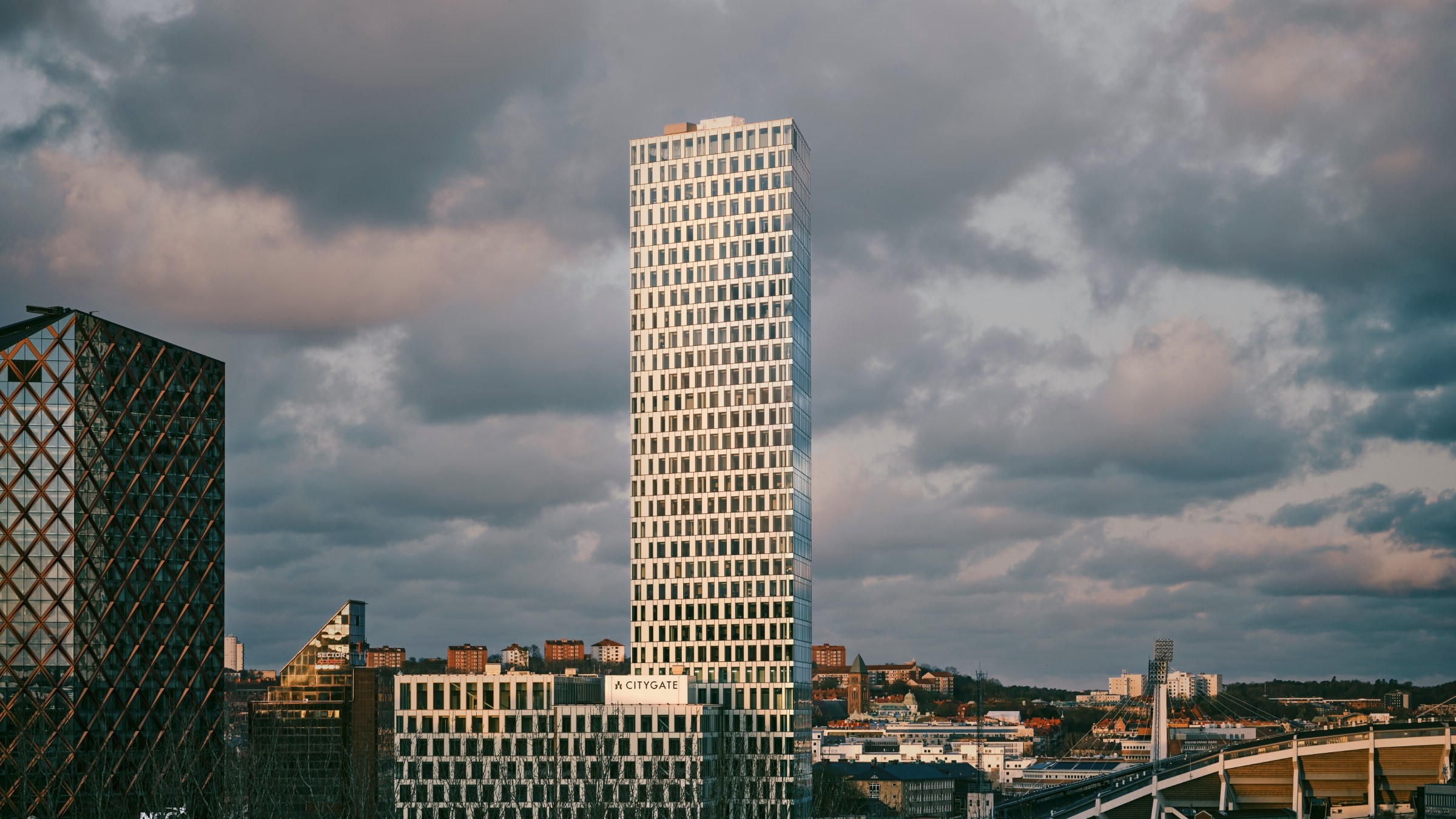 Modern stadsbild med hög byggnad under molnig himmel Hög modern skyskrapa i stadsmiljö med molnig himmel, med geometrisk arkitektur.