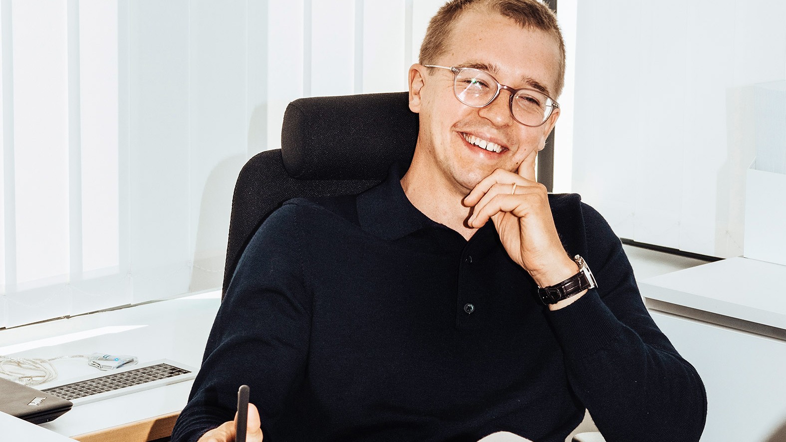 Beteendepsykologen Niklas Laninge Professional man in office attire seated at desk, holding a smartphone in a modern workspace.