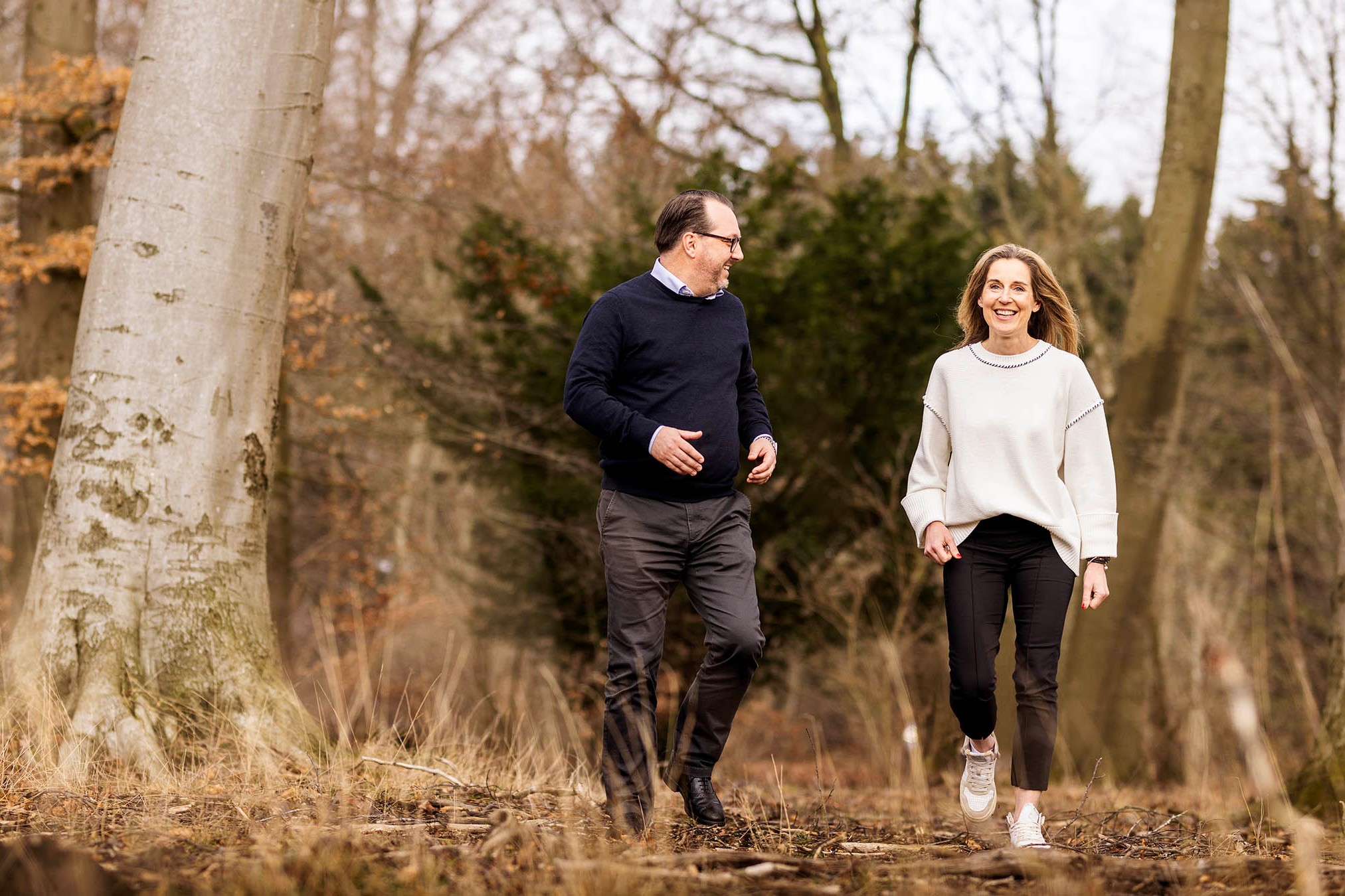 Människor som promenerar i skogen: Natur utomhus äventyrsscen Två personer går i ett skogsområde, klädda avslappnat i tröjor och byxor.
