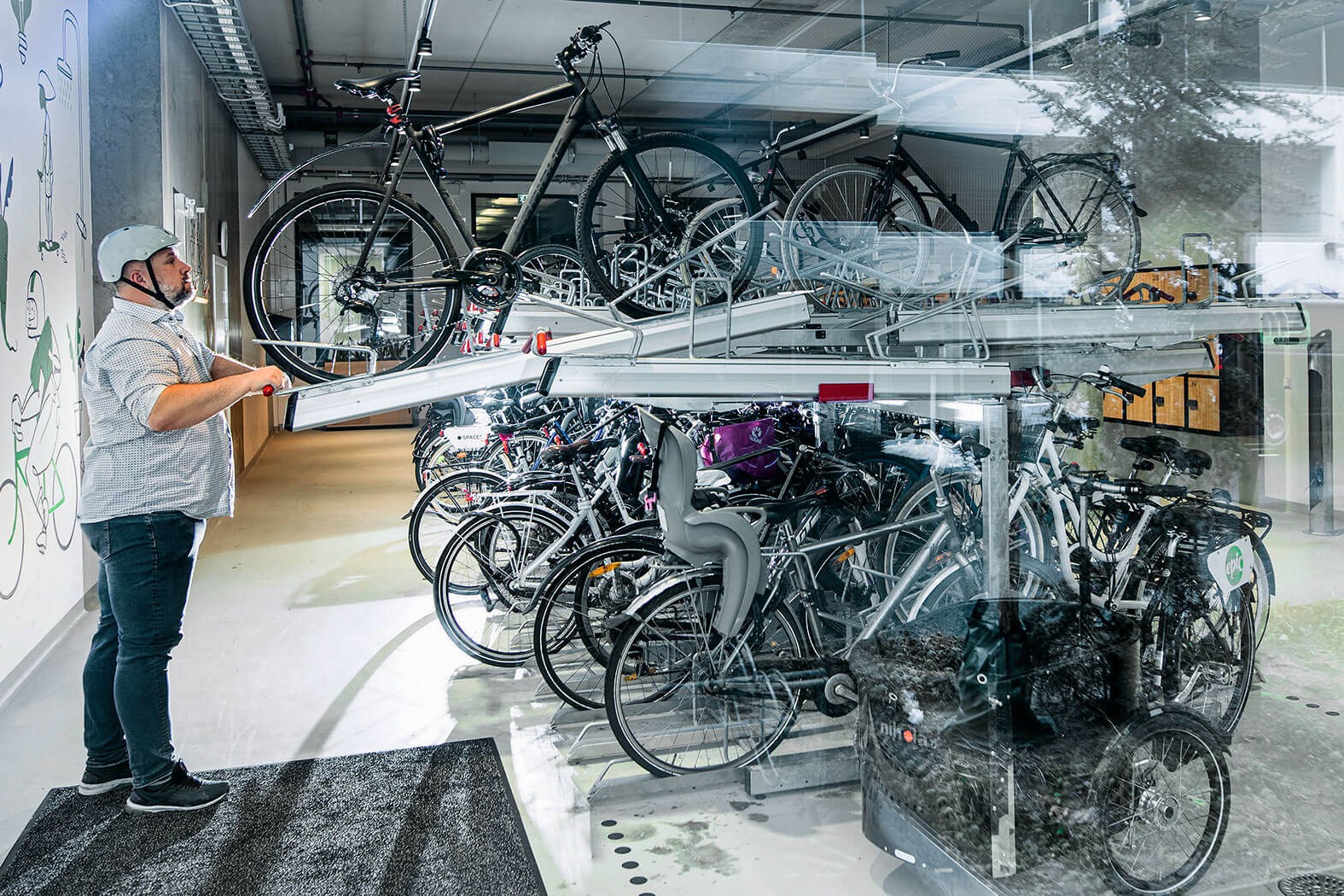 Modern lösning för cykelförvaring inomhus och utrymmesbesparare En person förvarar en cykel i ett tvåvånings inomhusställ med flera cyklar i en modern anläggning.