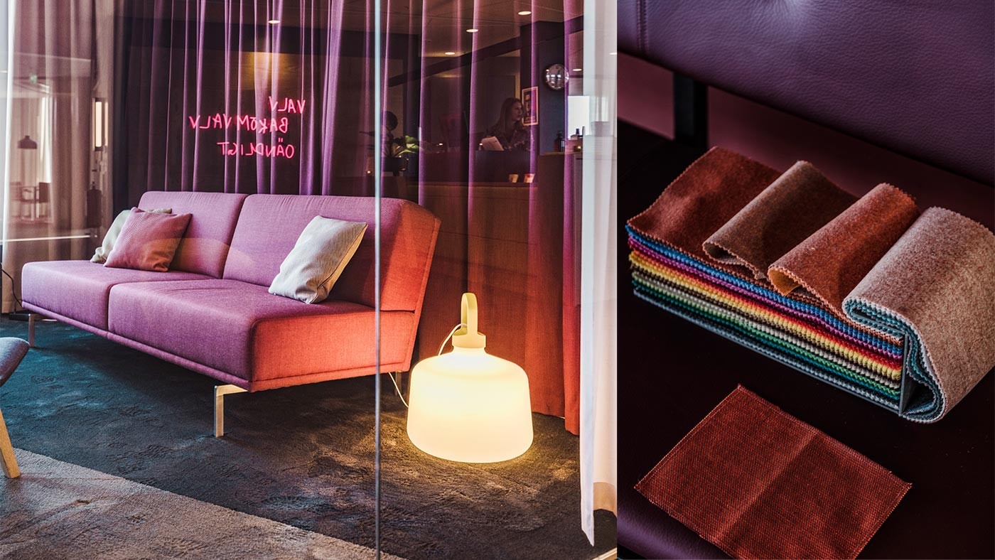 Modern rosa soffa med kuddar och färgglada tygprover på en mörk matta.